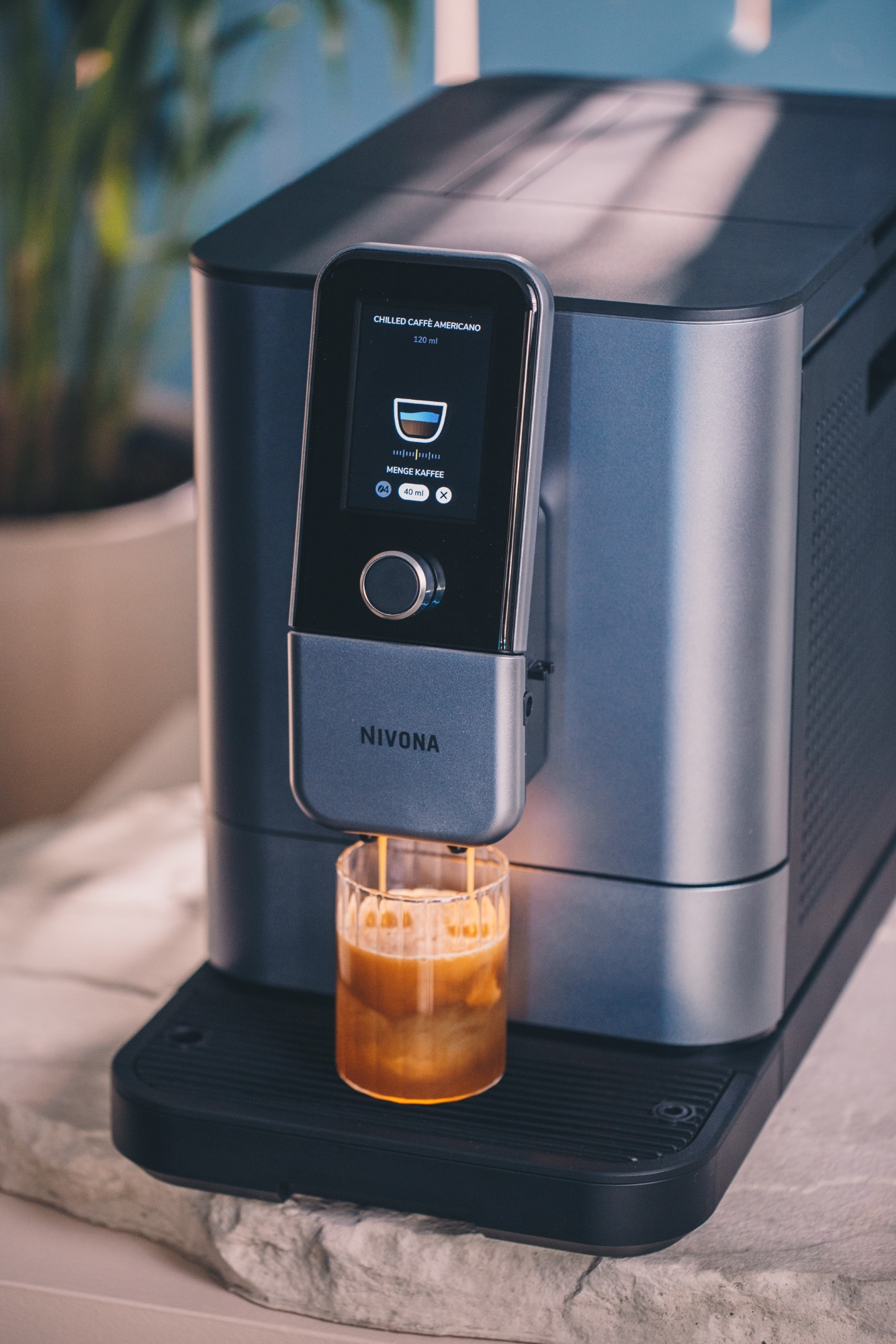 Ekspres do kawy dozujący kawę do szklanki, z widocznym wyświetlaczem i nowoczesnym designem.