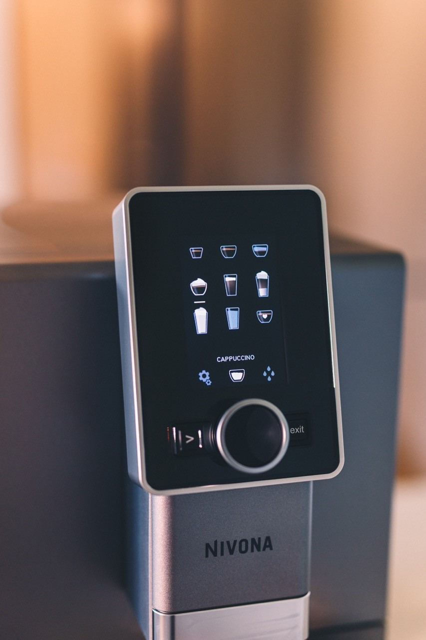 Zbliżenie na wyświetlacz ekspresu do kawy Nivona. Ekran dotykowy z różnymi opcjami kawy.