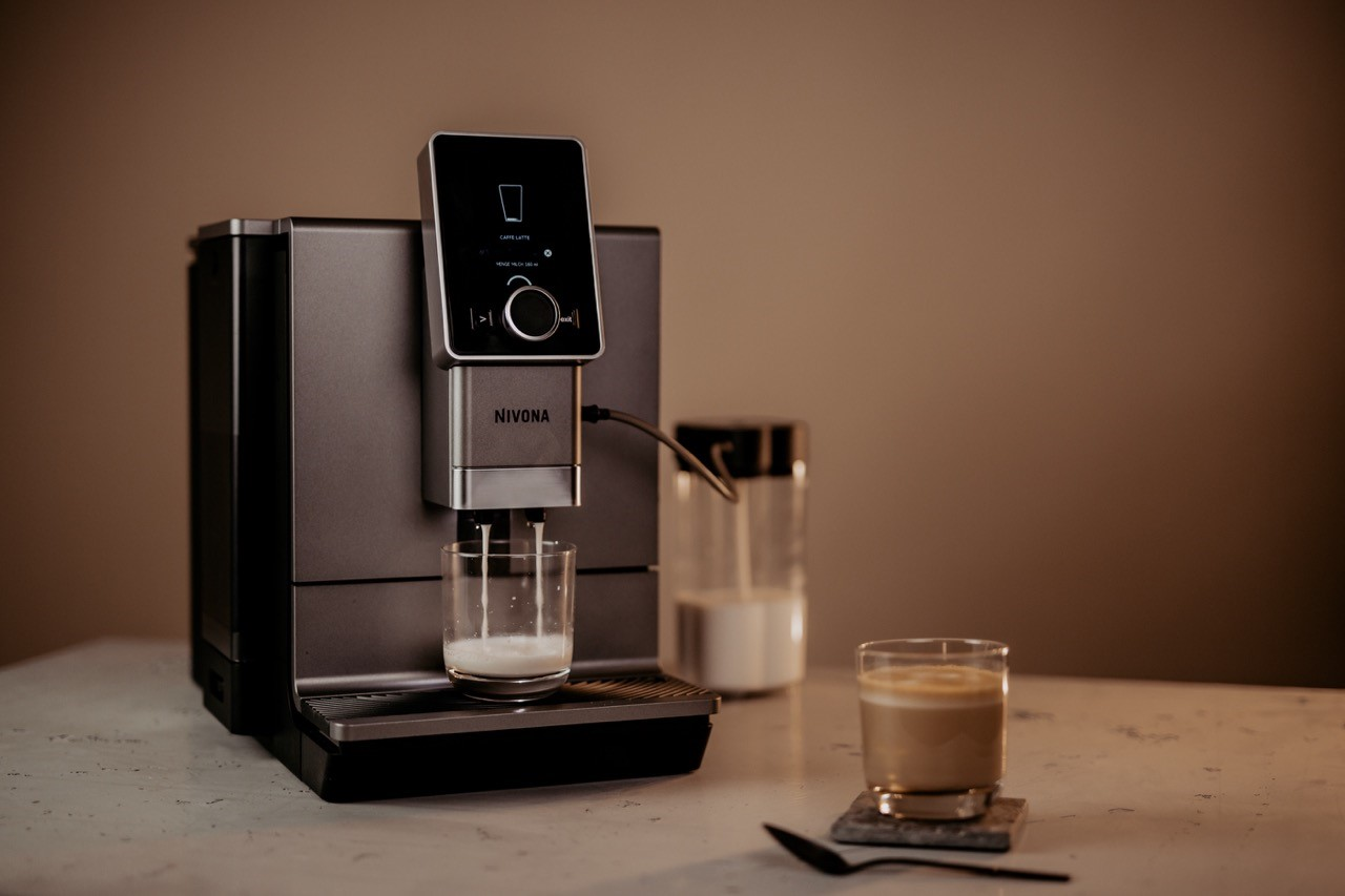 Ekspres do kawy nalewa kawę do szklanki. Na blacie jest również druga szklanka kawy.