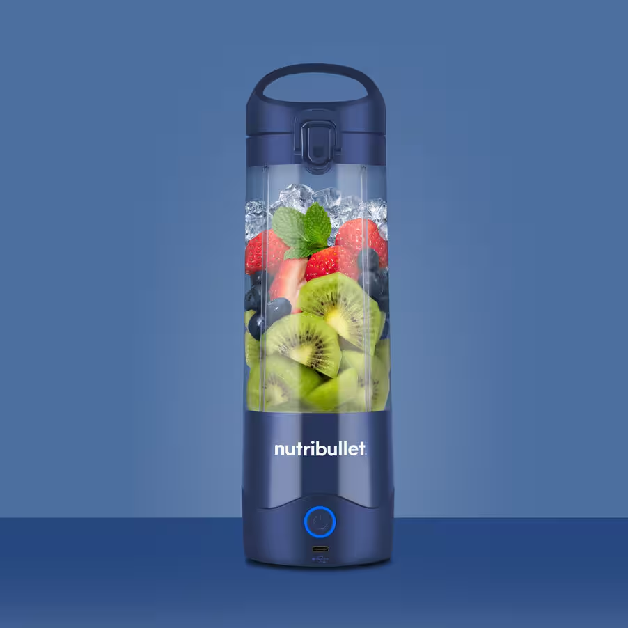 Transparente Blenderflasche mit Früchten und Eis. Blauer Hintergrund.