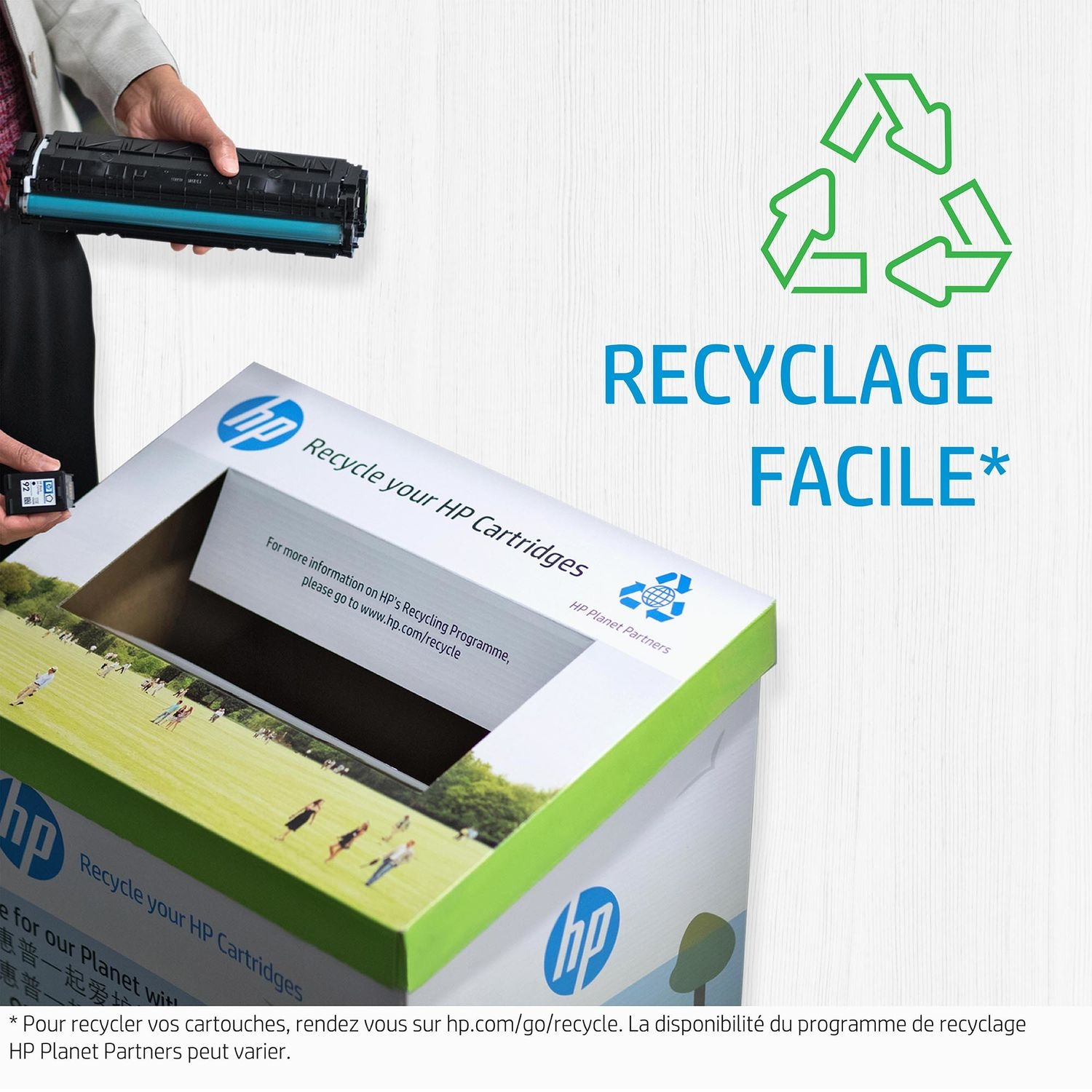 Main tenant une cartouche d'imprimante HP noire à côté d'une boîte de recyclage avec le logo et texte HP.