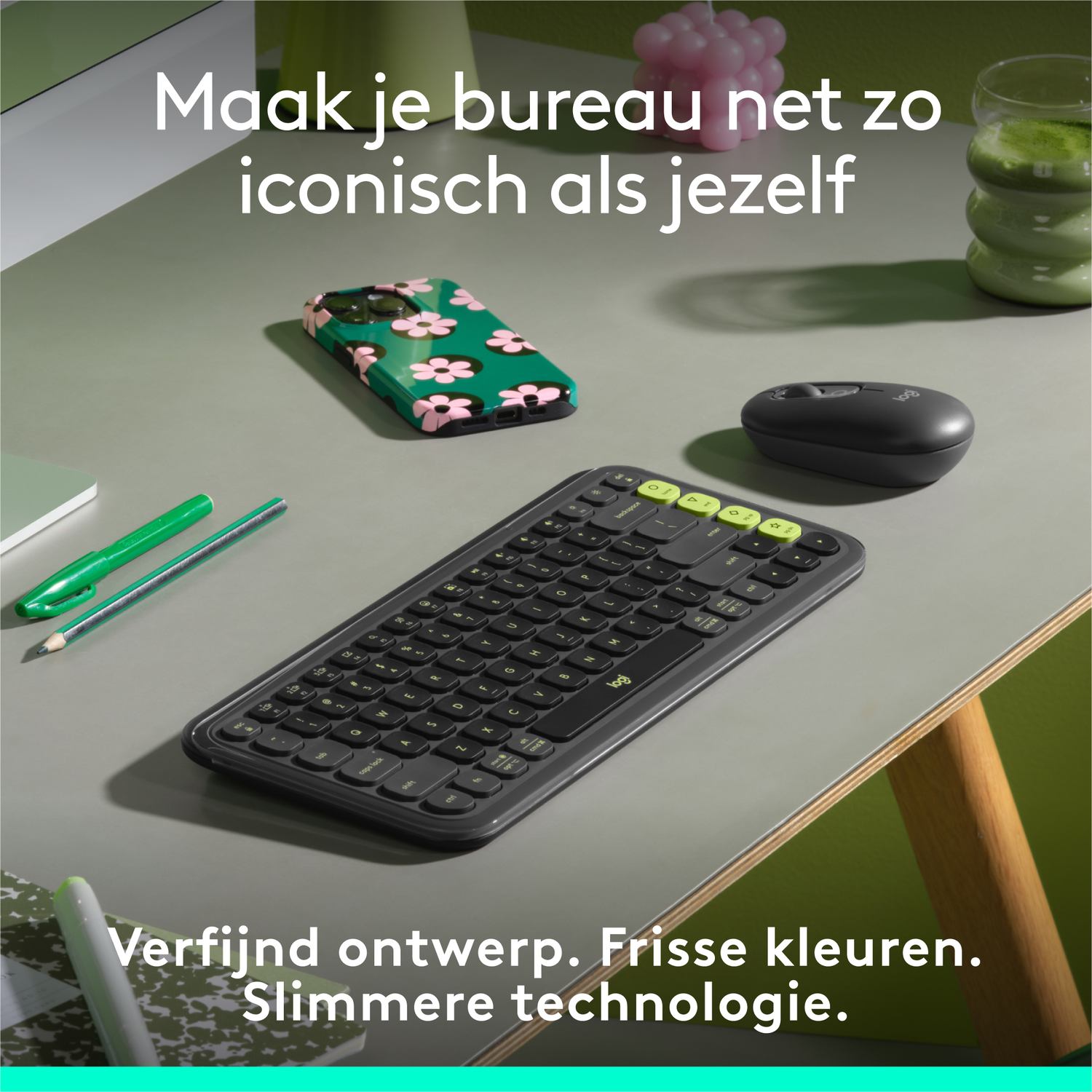 Een toetsenbord, muis en telefoonhoesje liggen op een grijs bureau. Het telefoonhoesje heeft roze bloemen.