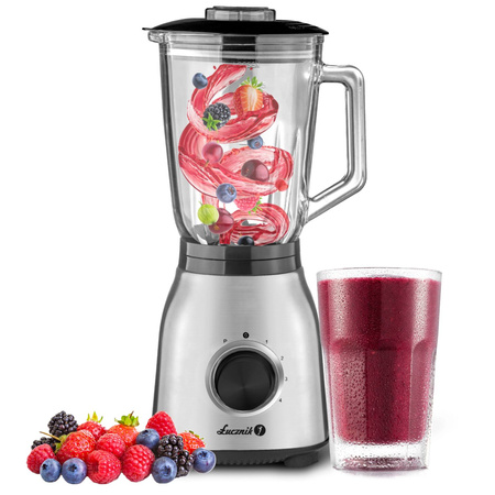 Blender z owocami w szkle i szklanka smoothie obok.