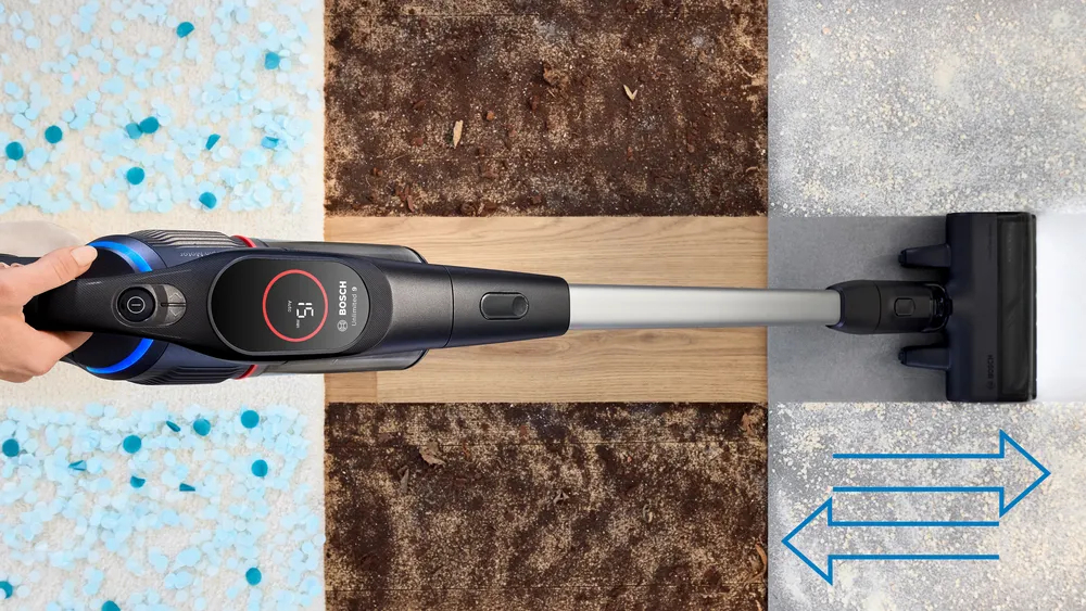 Widok z góry na czarno-niebieski odkurzacz czyszczący podłogę o różnych fakturach.