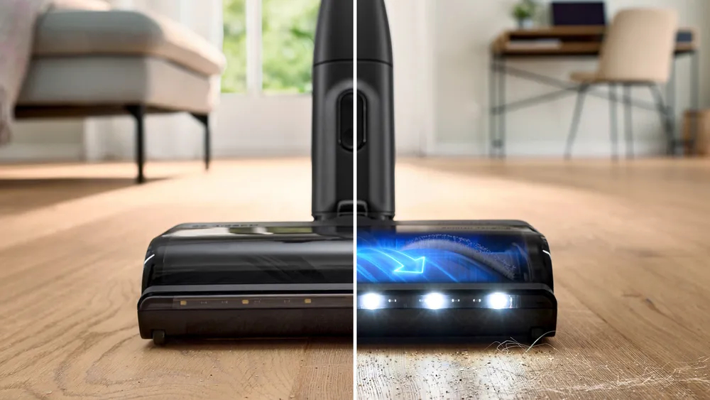 Zbliżenie głowicy odkurzacza, pokazujące działanie czyszczące na drewnianej podłodze. Strzałki wskazują kierunek.