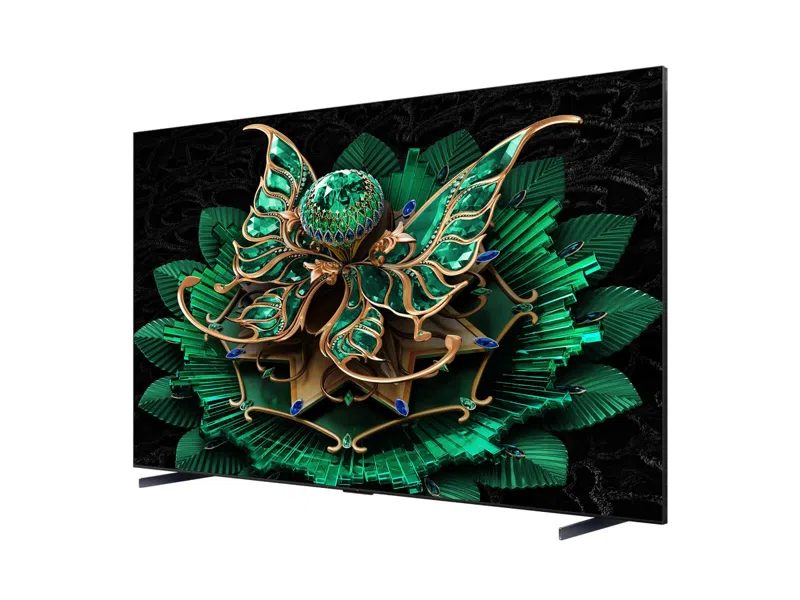 Ein Fernseher mit einem grünen und goldenen Blumendesign auf schwarzem Hintergrund. Der Fernseher steht auf einer weißen Fläche.