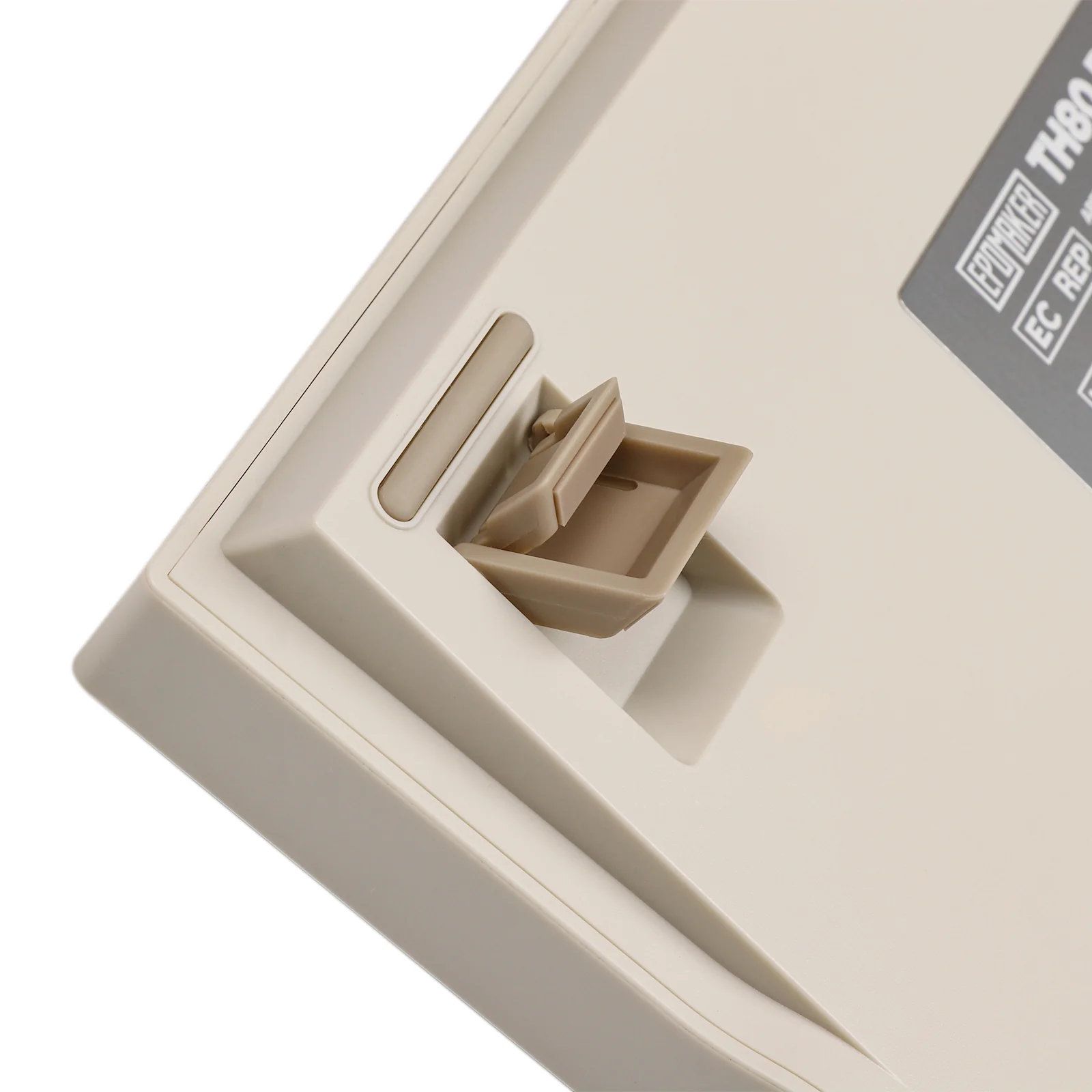 Zbliżenie beżowej podstawy klawiatury z narzędziem do wyjmowania klawiszy.