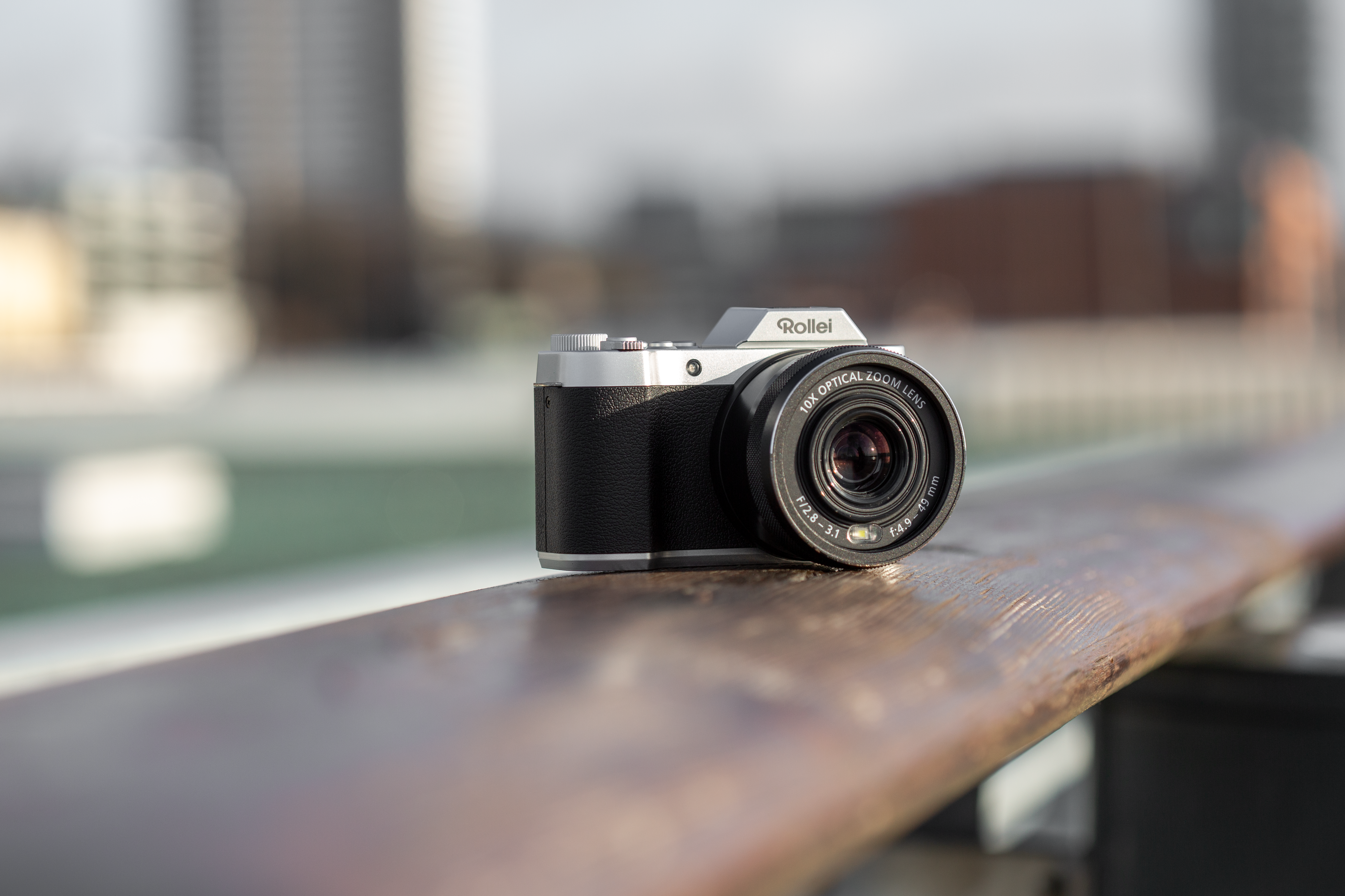 Una fotocamera Rollei su un corrimano di legno, con sfondo sfocato.