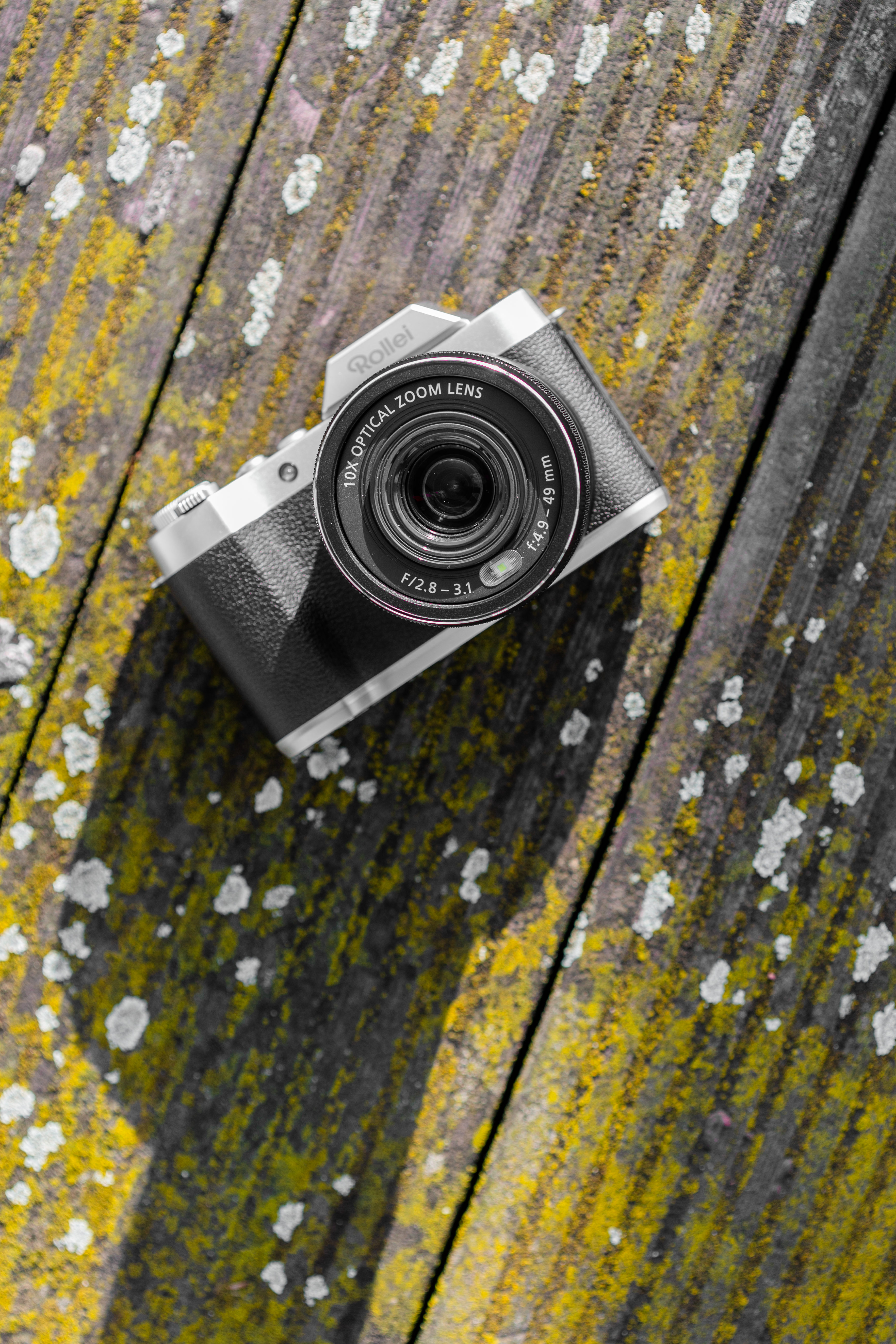 Una fotocamera nera e argento su una superficie di legno.