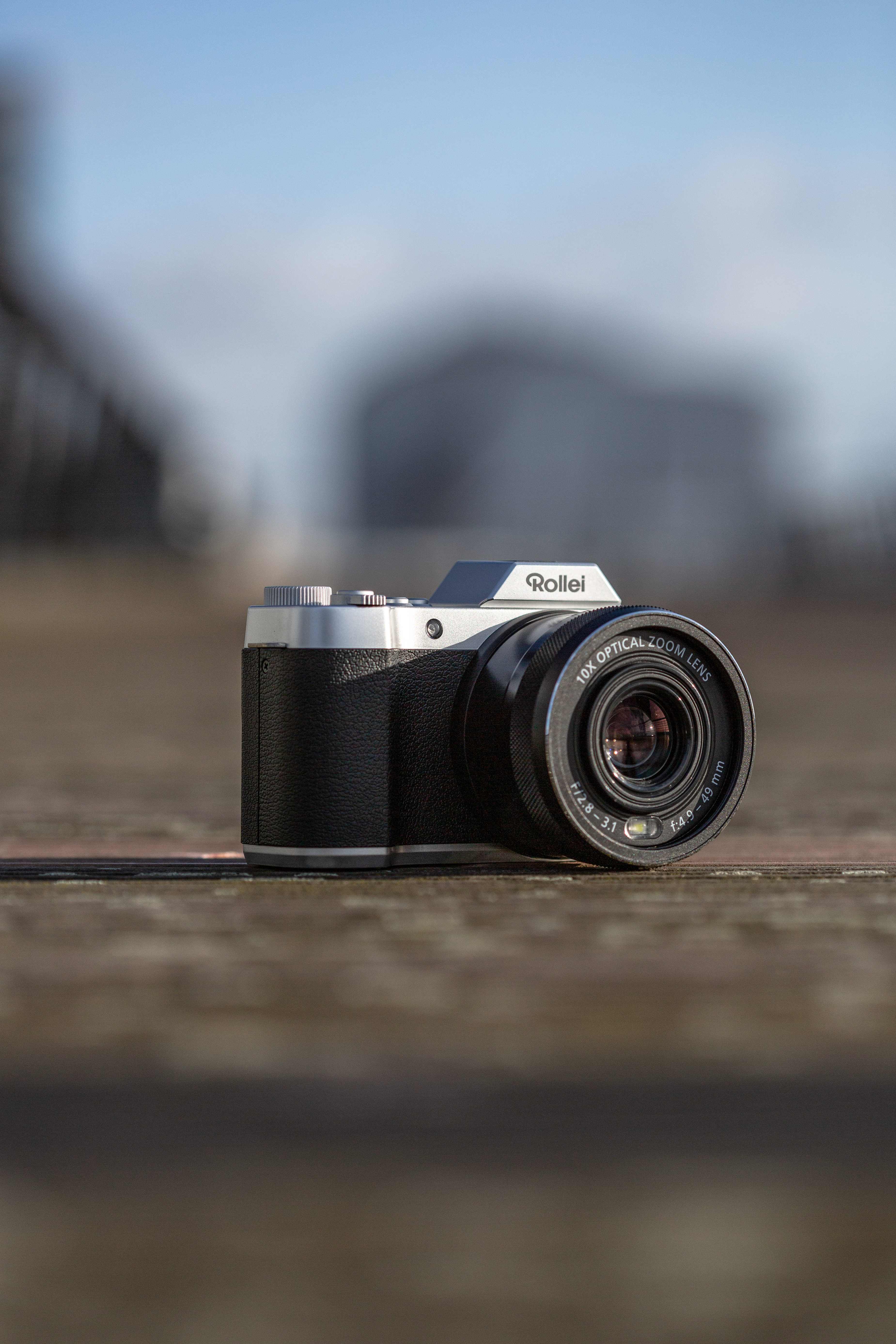 Una fotocamera Rollei con corpo nero e parte superiore argentata, su una superficie di legno.