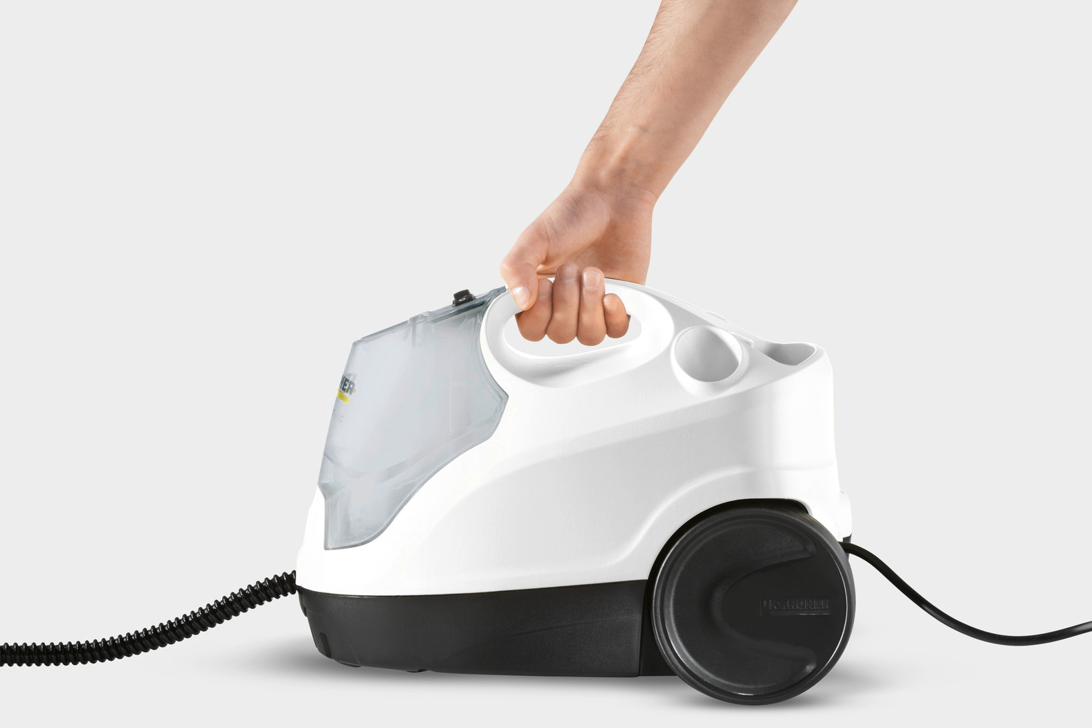 Ręka trzymająca biało-czarną myjkę parową, z widocznym czarnym przewodem.