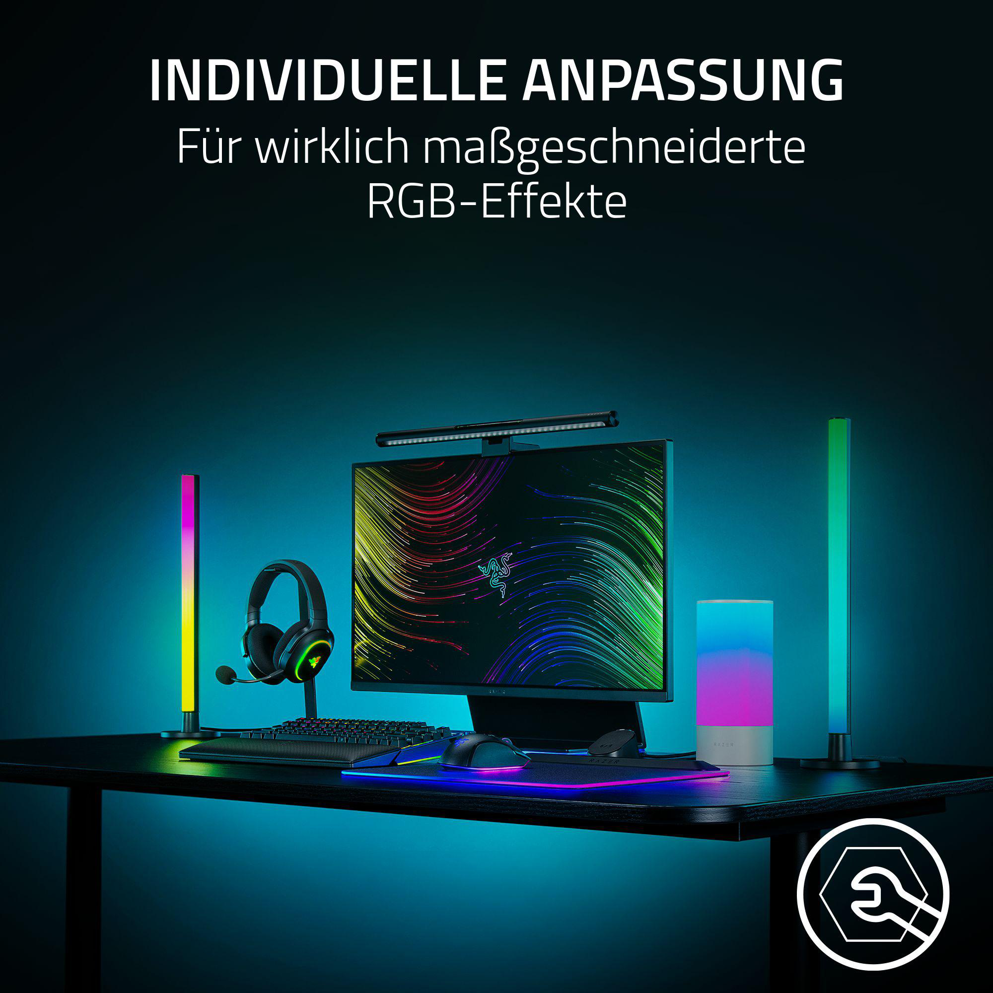 Ein Gaming-Setup mit Monitor, Tastatur, Kopfhörern und farbenfrohen RGB-Lichtern auf einem schwarzen Schreibtisch.