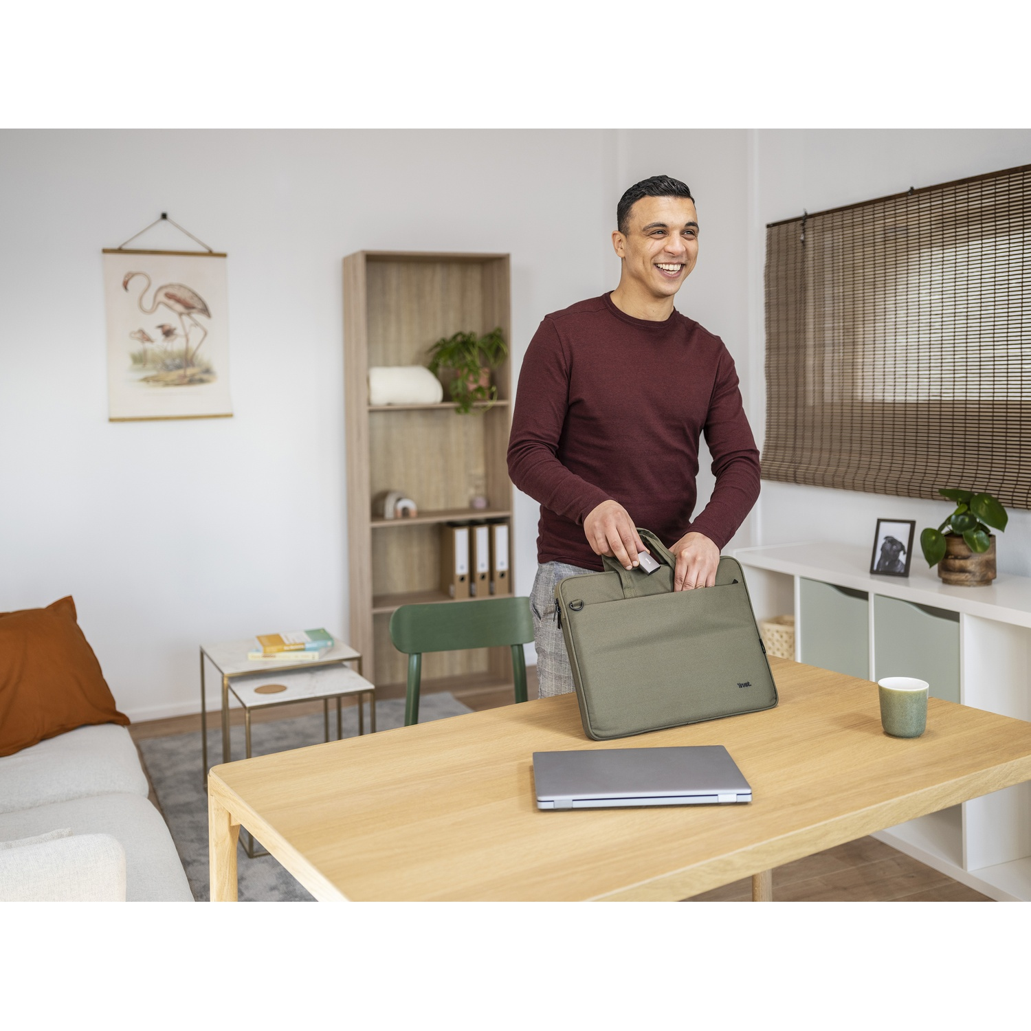 Uomo con una borsa per laptop vicino a un tavolo con un laptop sopra.