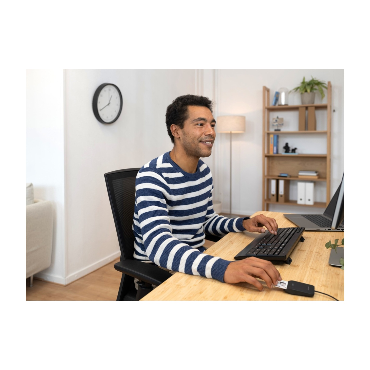 Un uomo a una scrivania, che lavora su un laptop con una tastiera e altri accessori.
