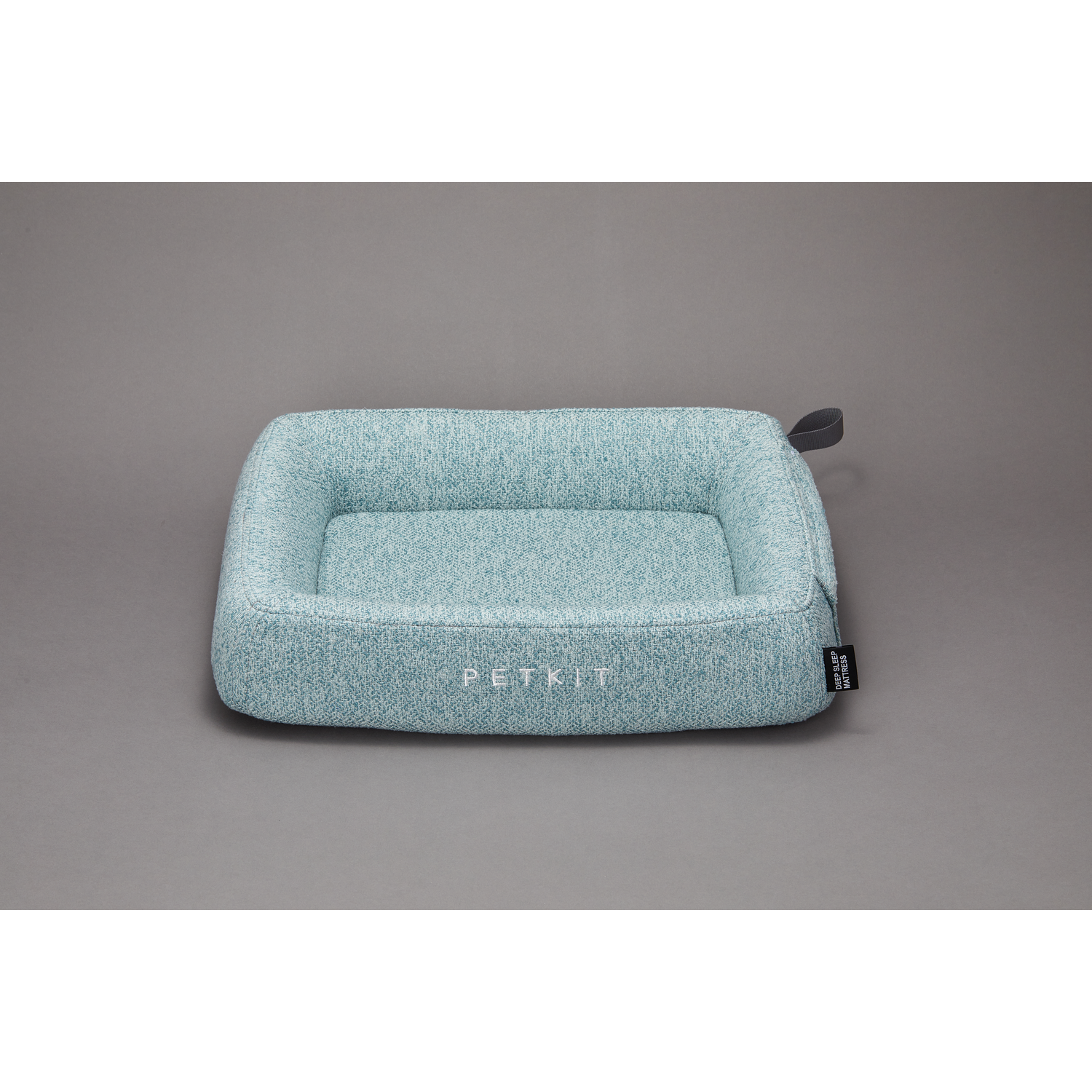 A light blue pet bed is shown on a gray surface. The bed is rectangular with a low side.