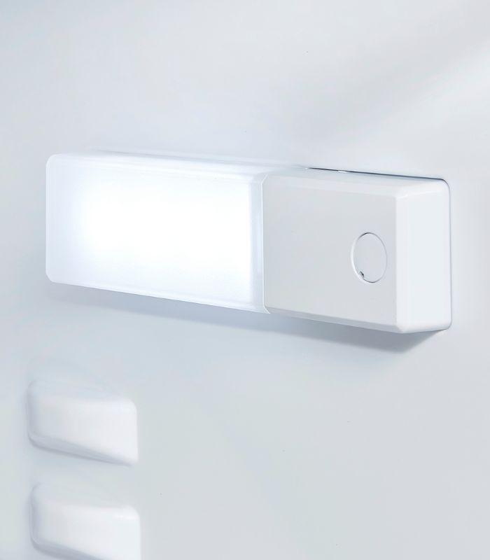 Weiße, rechteckige Leuchte mit Knopf an weißer Wand. Das Licht ist an.