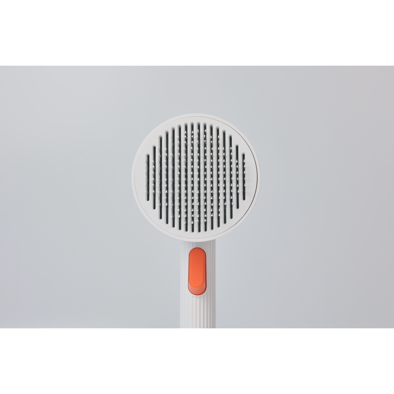 White pet grooming brush with an orange button and a white background.