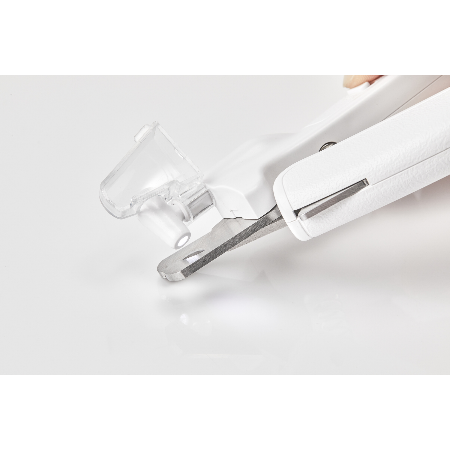 Een witte nagelknipper met een transparante plastic hoes, schuin op een wit oppervlak.