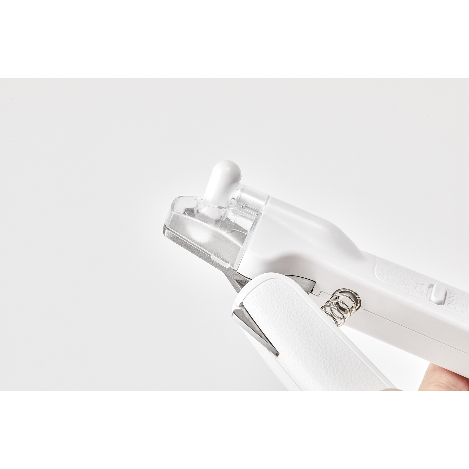 A white nail clipper with a blade open, on a white background.