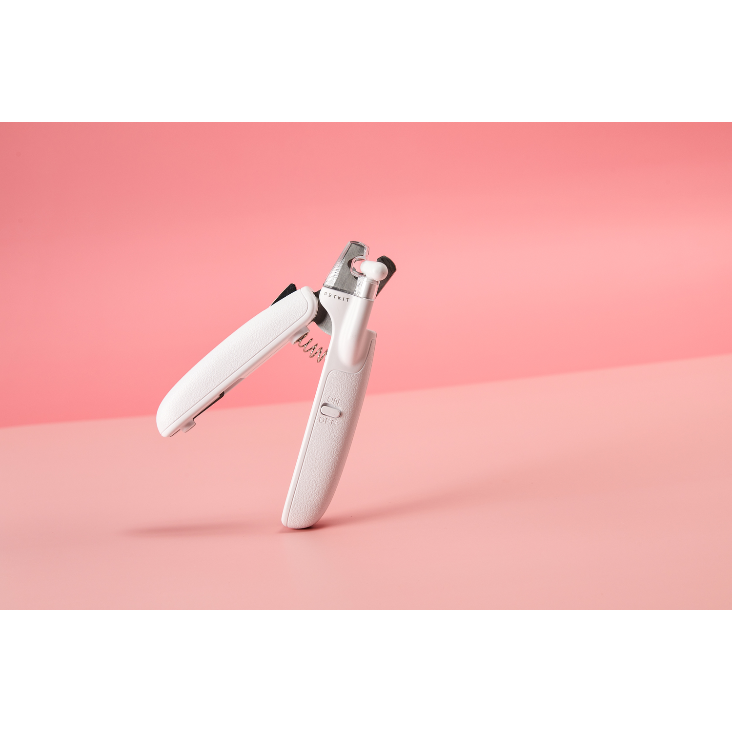 White pet nail clippers on a pink background.