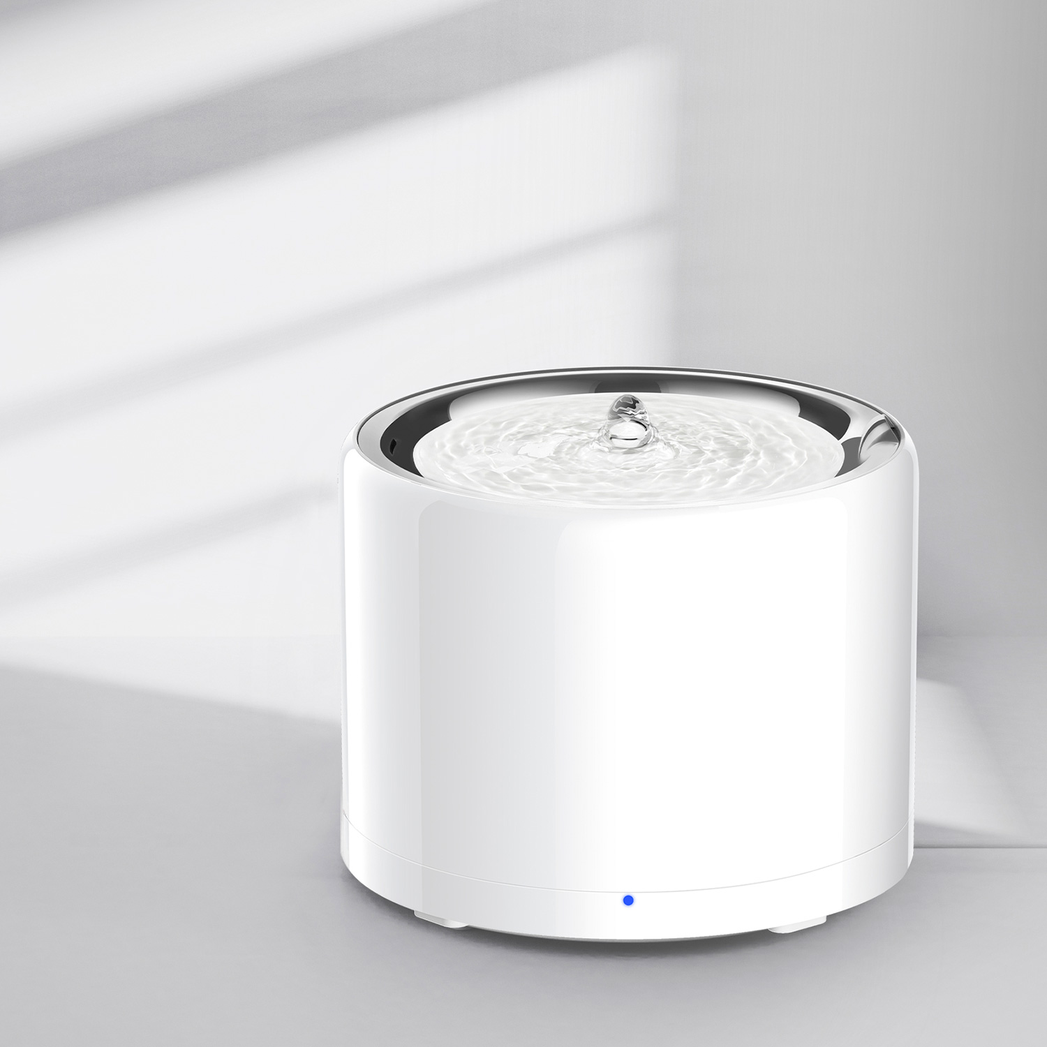 A white pet water fountain with a small spout and bubbling water, casting a shadow.