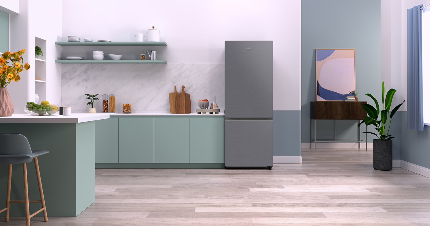 Modern kitchen with a gray refrigerator. Light wood floor, mint green cabinets, and a blue wall.