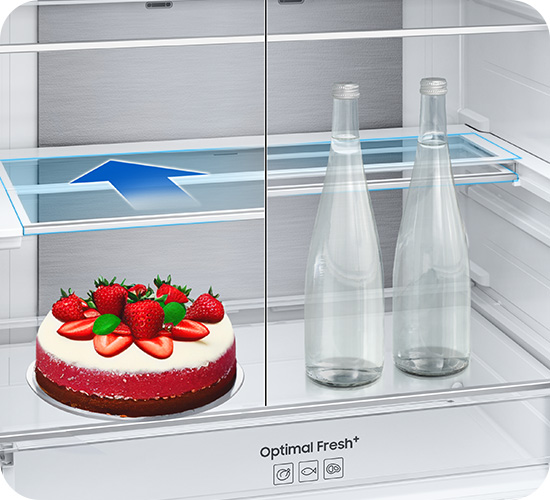 Refrigerator interior with a cake, strawberries, water bottles, and an arrow pointing to the shelf.