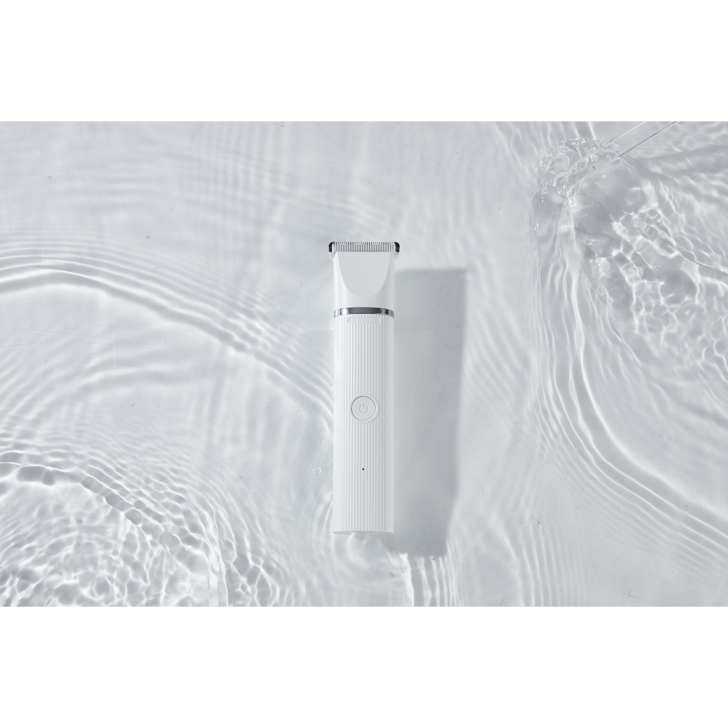 White shaver in water. Ripples visible. Clean, minimalist aesthetic.