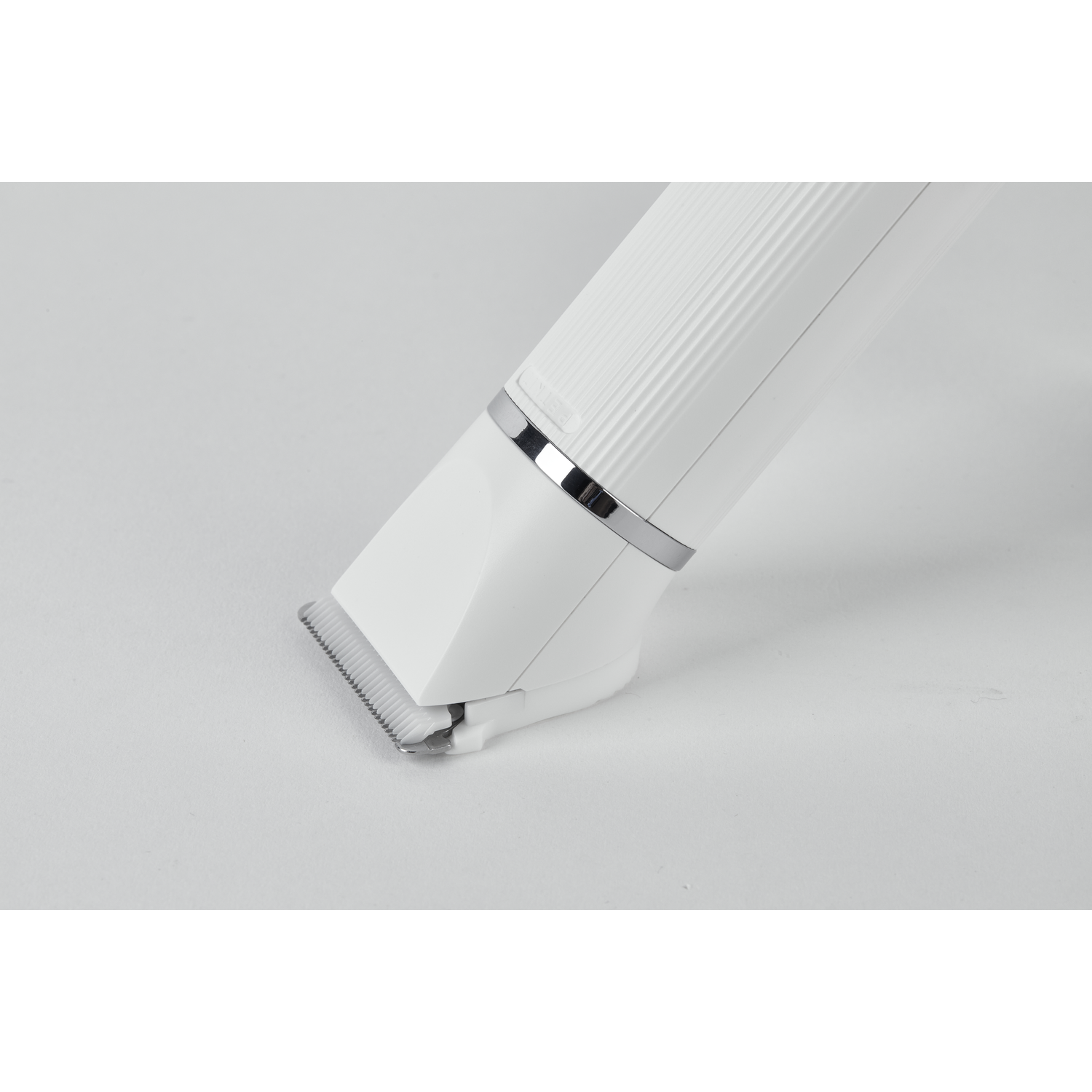 Close-up of a white pet grooming trimmer with a metallic accent and angled blade.