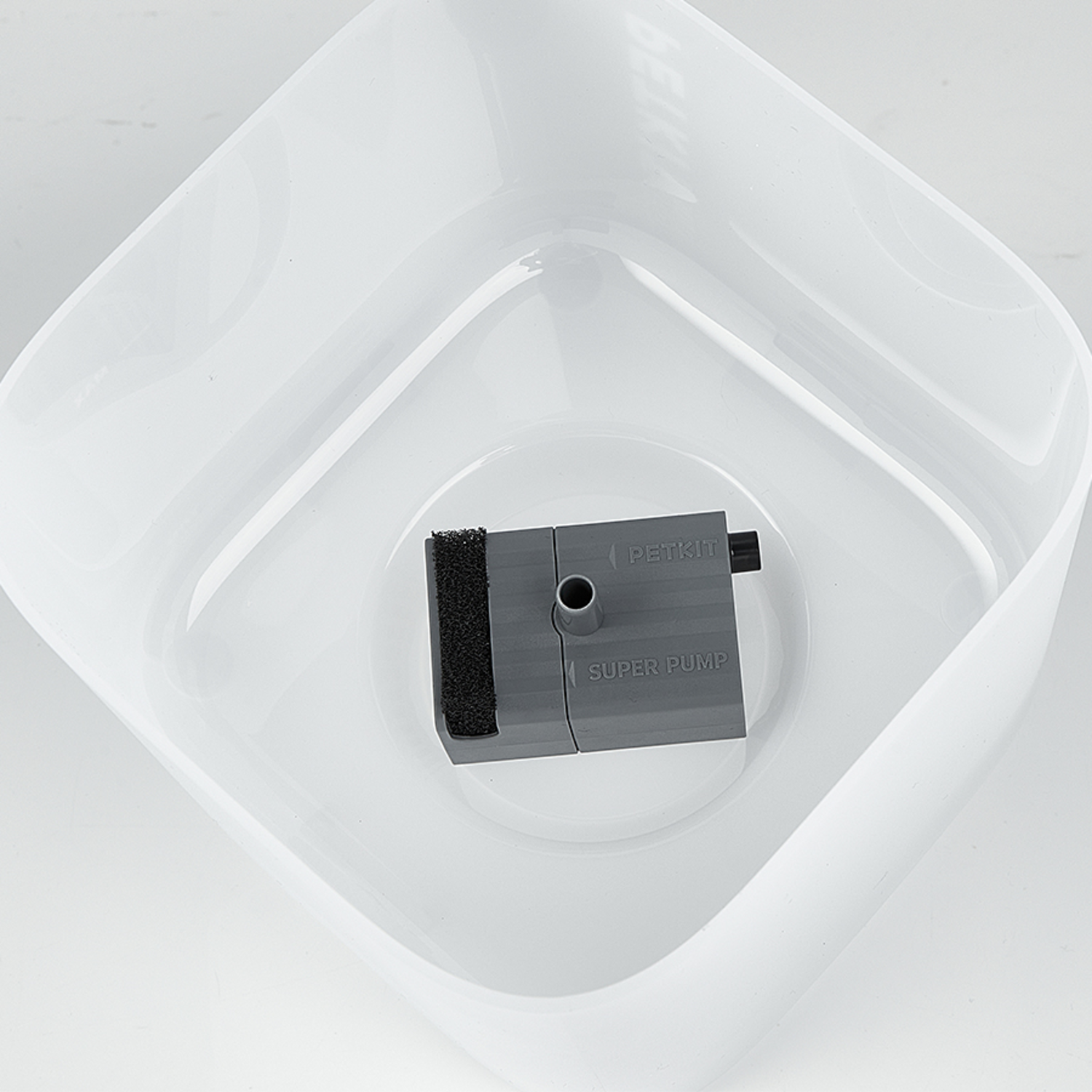 A gray pump inside a white pet water bowl. The pump is labeled "SUPER PUMP" and "PETKIT".