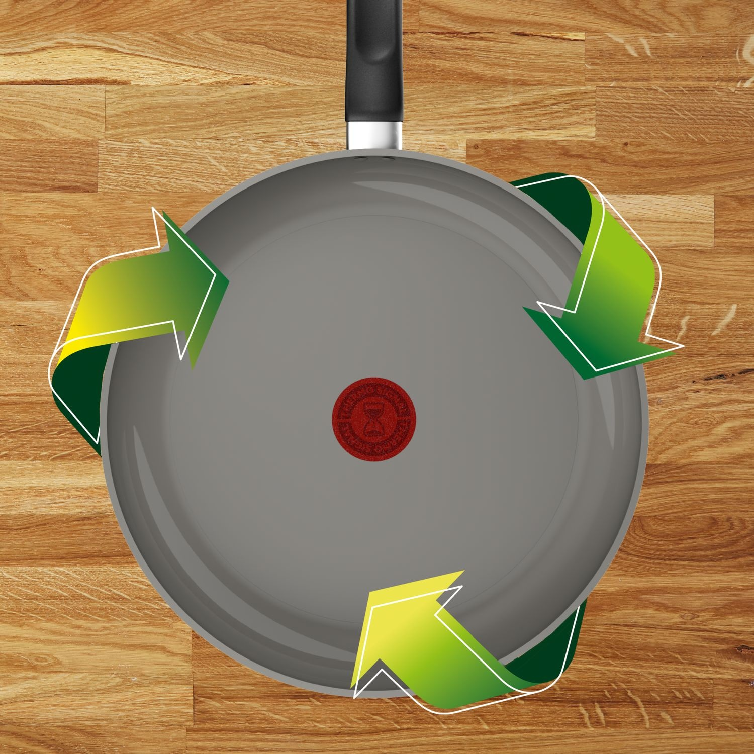 A gray pan with a black handle on a wooden surface. Green arrows circle the pan, suggesting recycling. A red logo is in the center.