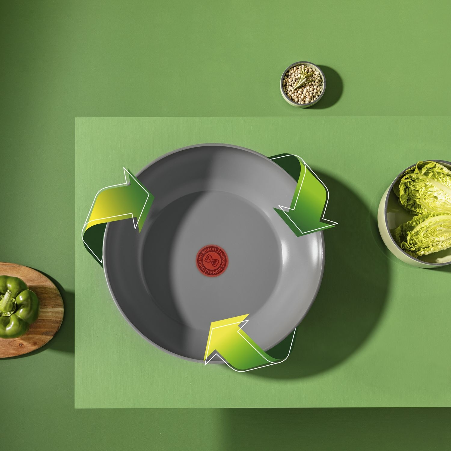 Grijze koekenpan met rode kern omringd door groene pijlen. Groene achtergrond.