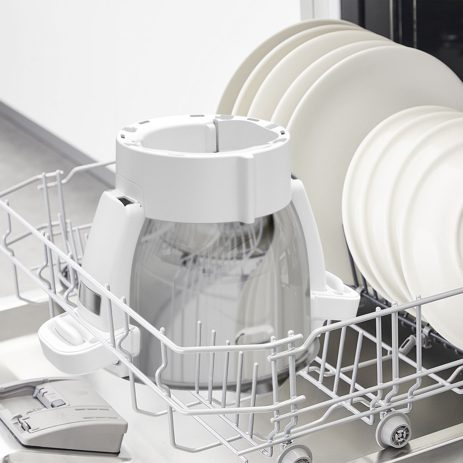 Dishwasher with a white cleaning device inside, surrounded by clean white plates and other items.