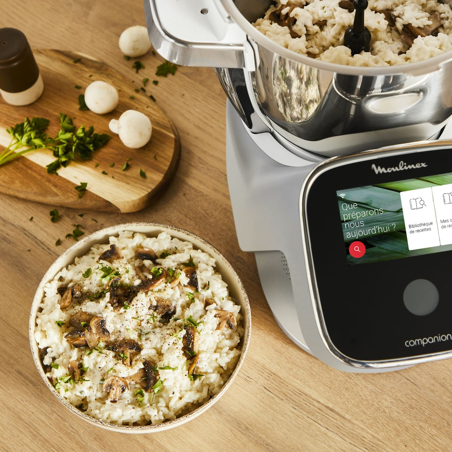 A bowl of risotto with mushrooms and a Moulinex i-Companion Pro, mushrooms, and wooden board.