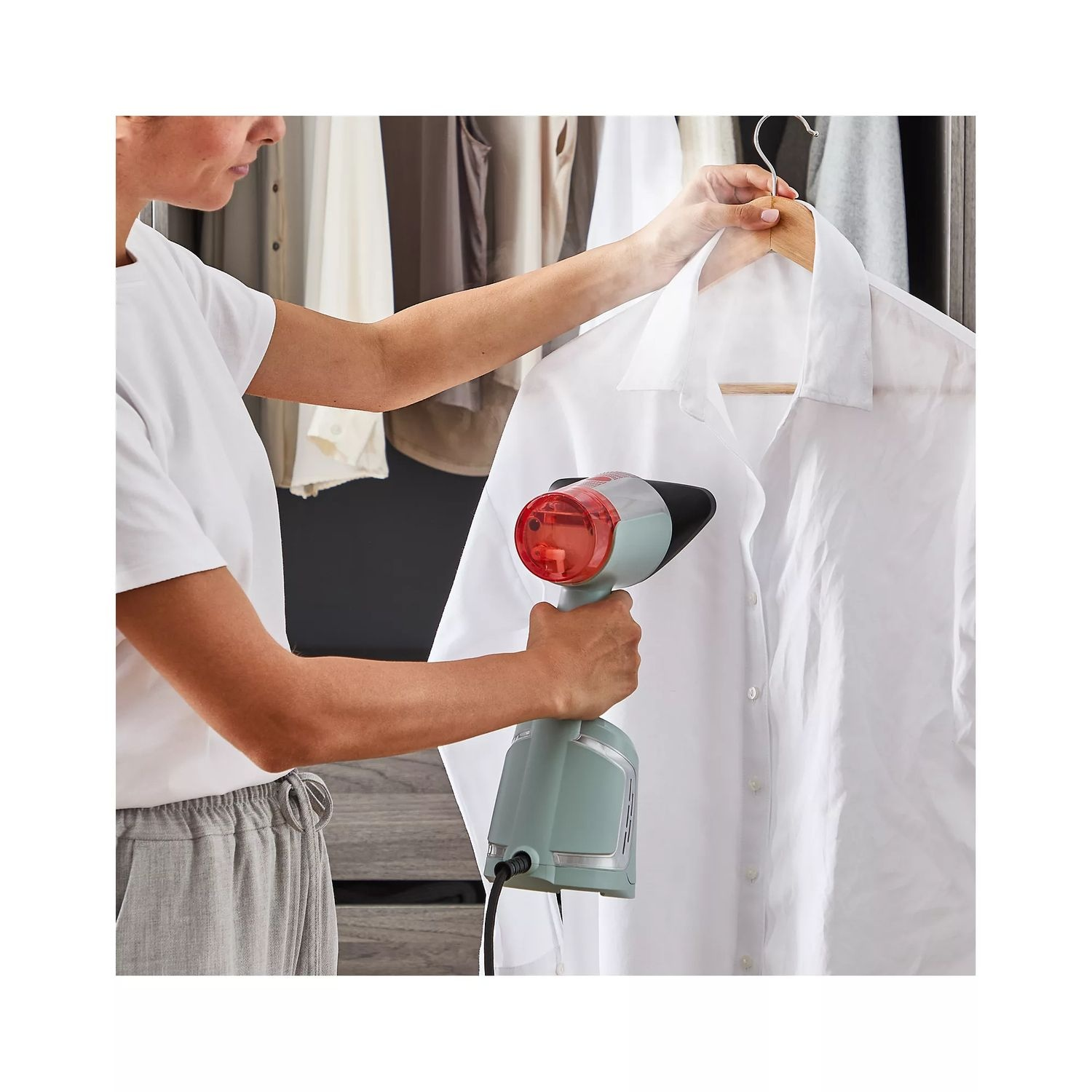 A woman ironing a white shirt with a steamer.