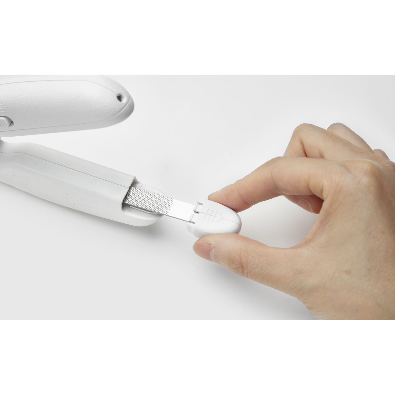 A hand holding a white nail file, removing a small part of a device.