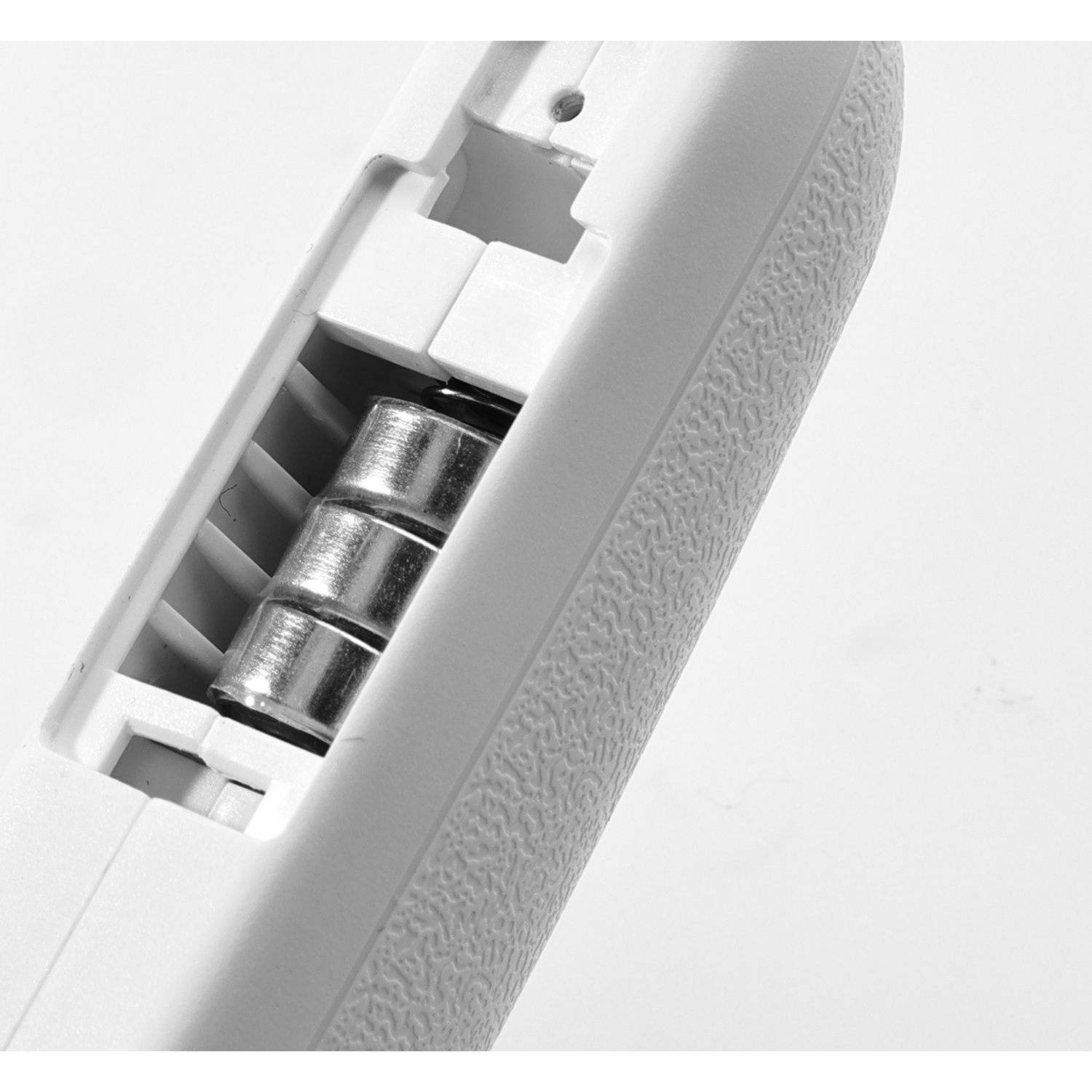 Open battery compartment with batteries inside. White object. Close-up shot.