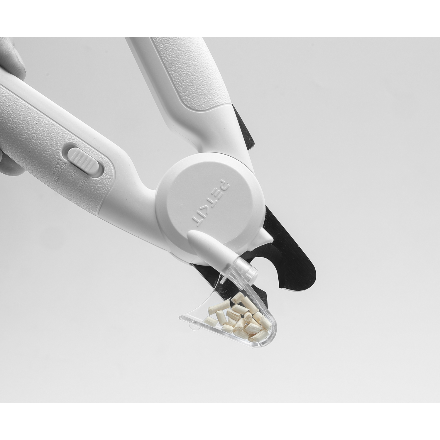 A white PETKIT nail clipper with a clear container holding small, white pills.