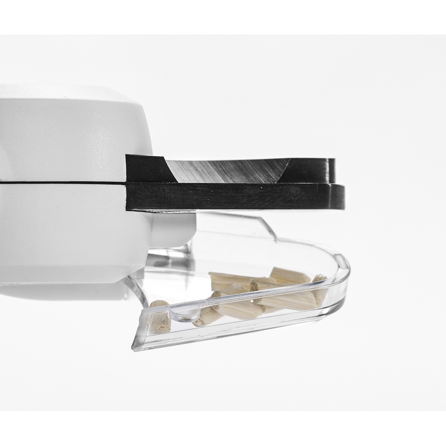 A white, closed, kitchen appliance with a black blade. A clear tray collects chopped wood.
