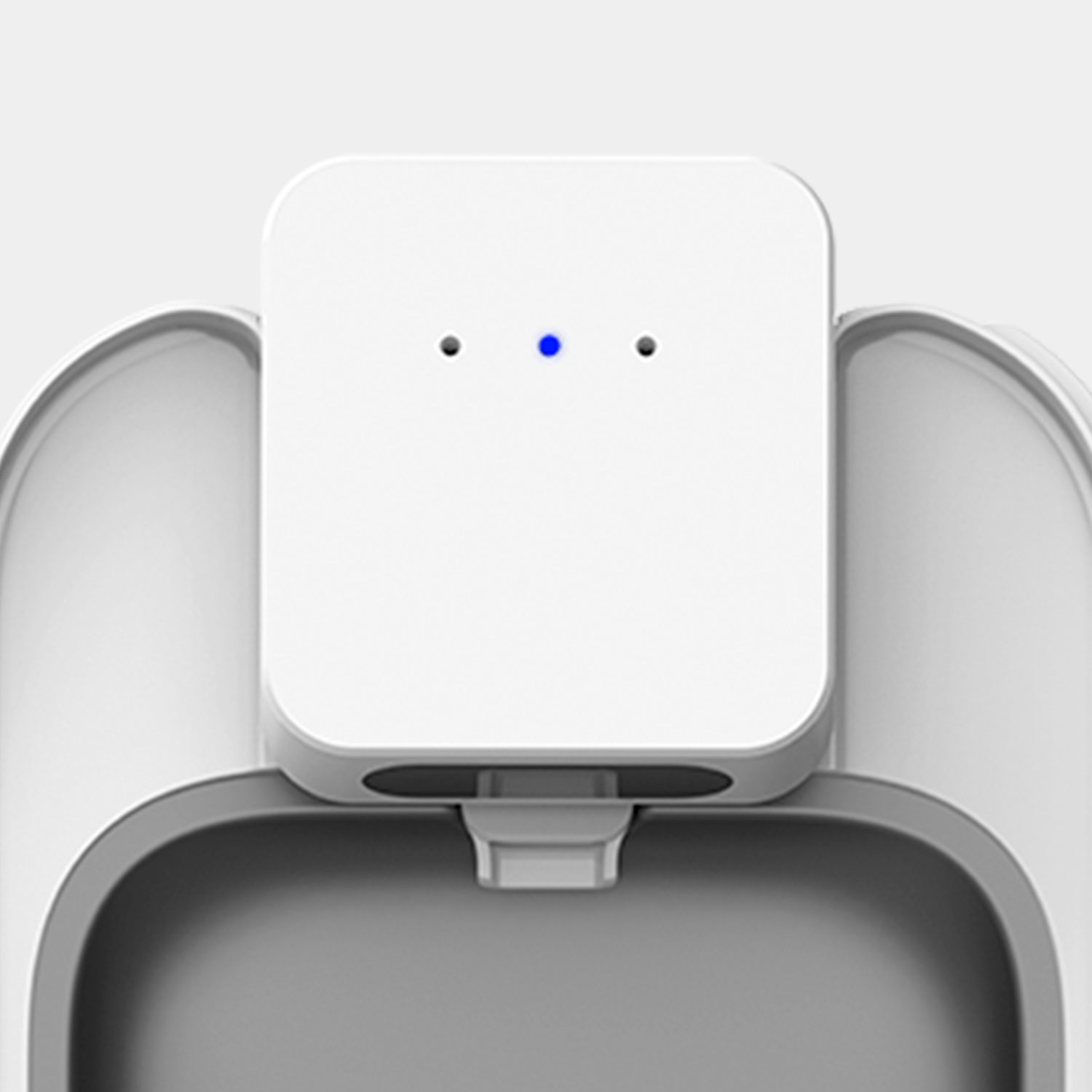 White device with three dots. One is blue. Appears to be a charging station.