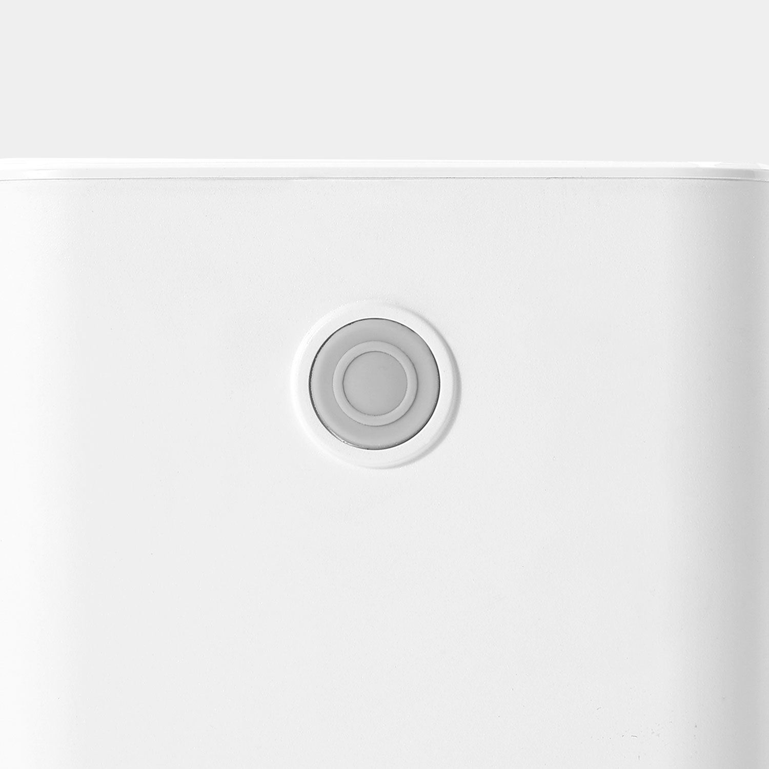 Close-up of a white, rounded object with a grey circular button in the center.