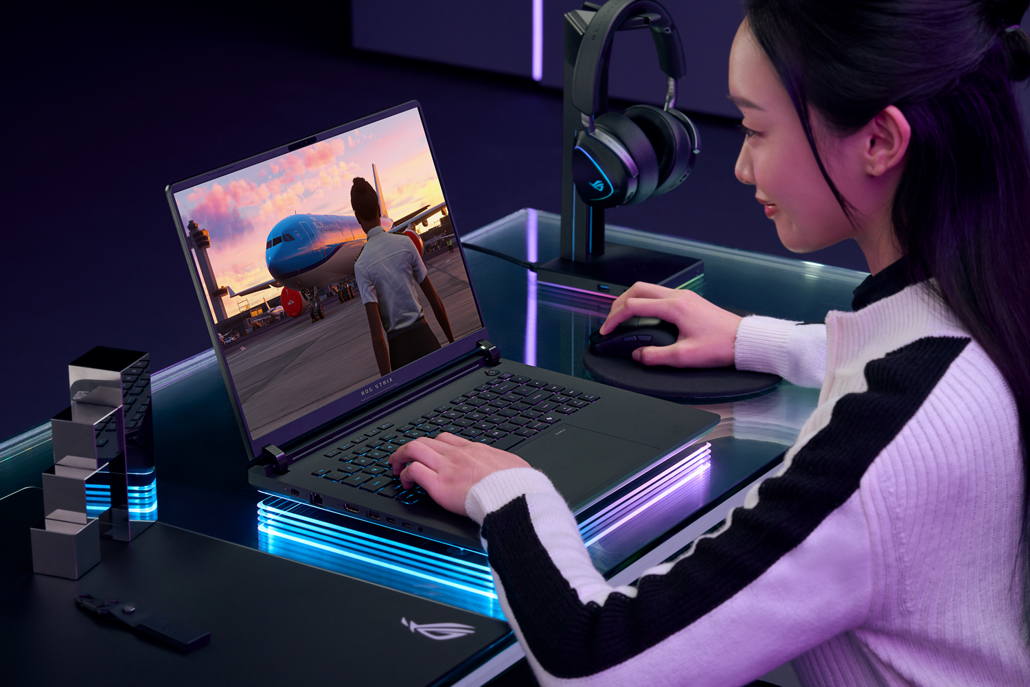Mujer usando una laptop que muestra un simulador de vuelo. Hay auriculares y un ratón en el escritorio.