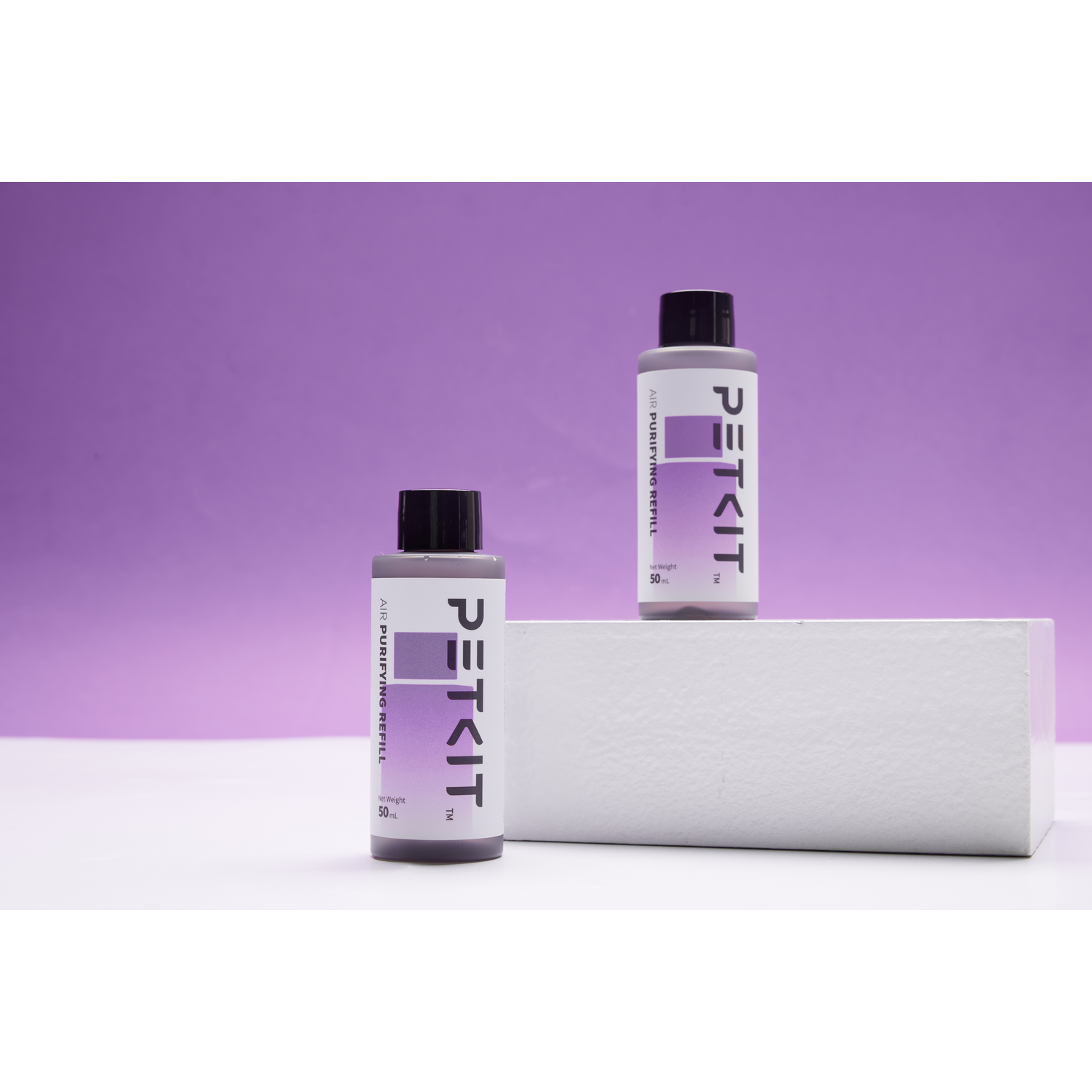 Two PETKIT air purifying refill bottles on a white block against a purple background.