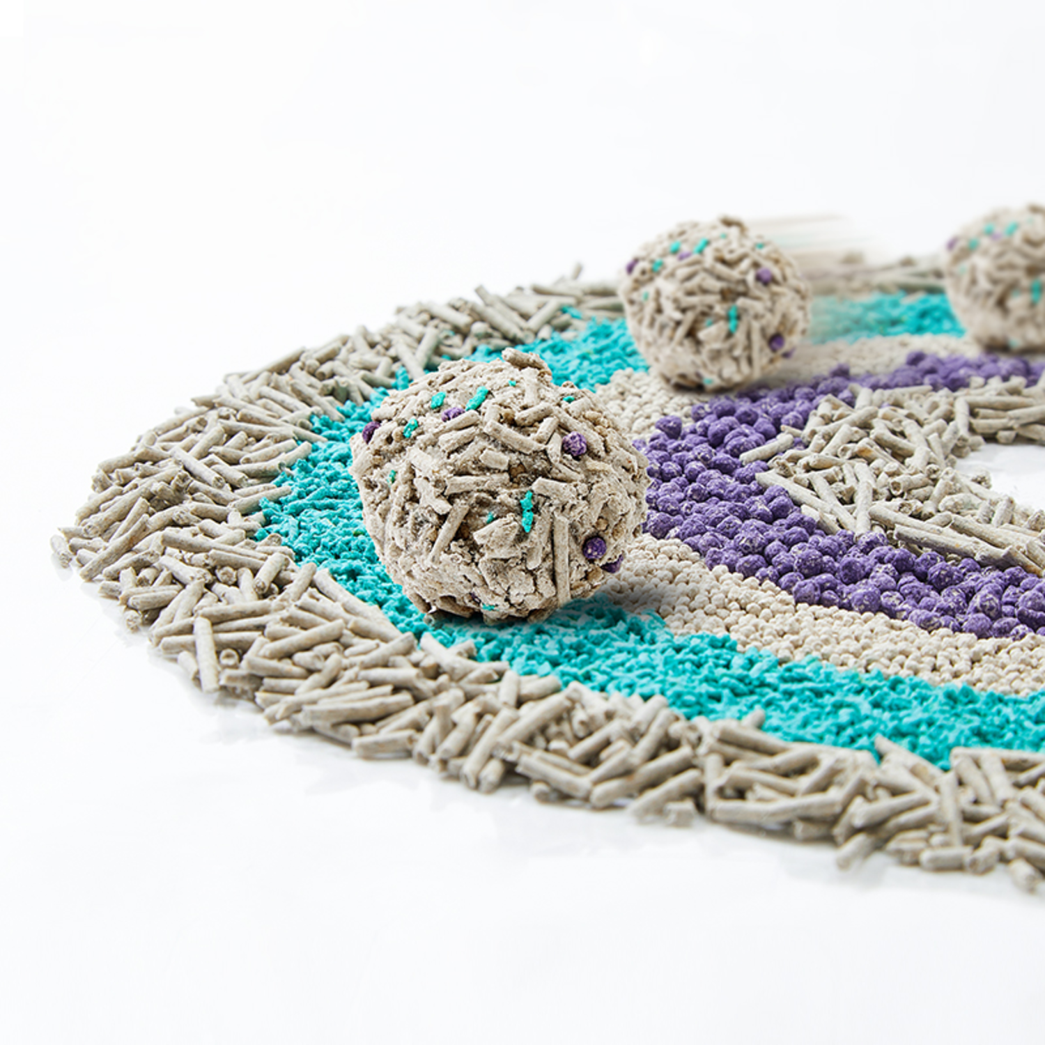 Cat litter with three balls. The litter has various colors. White background.