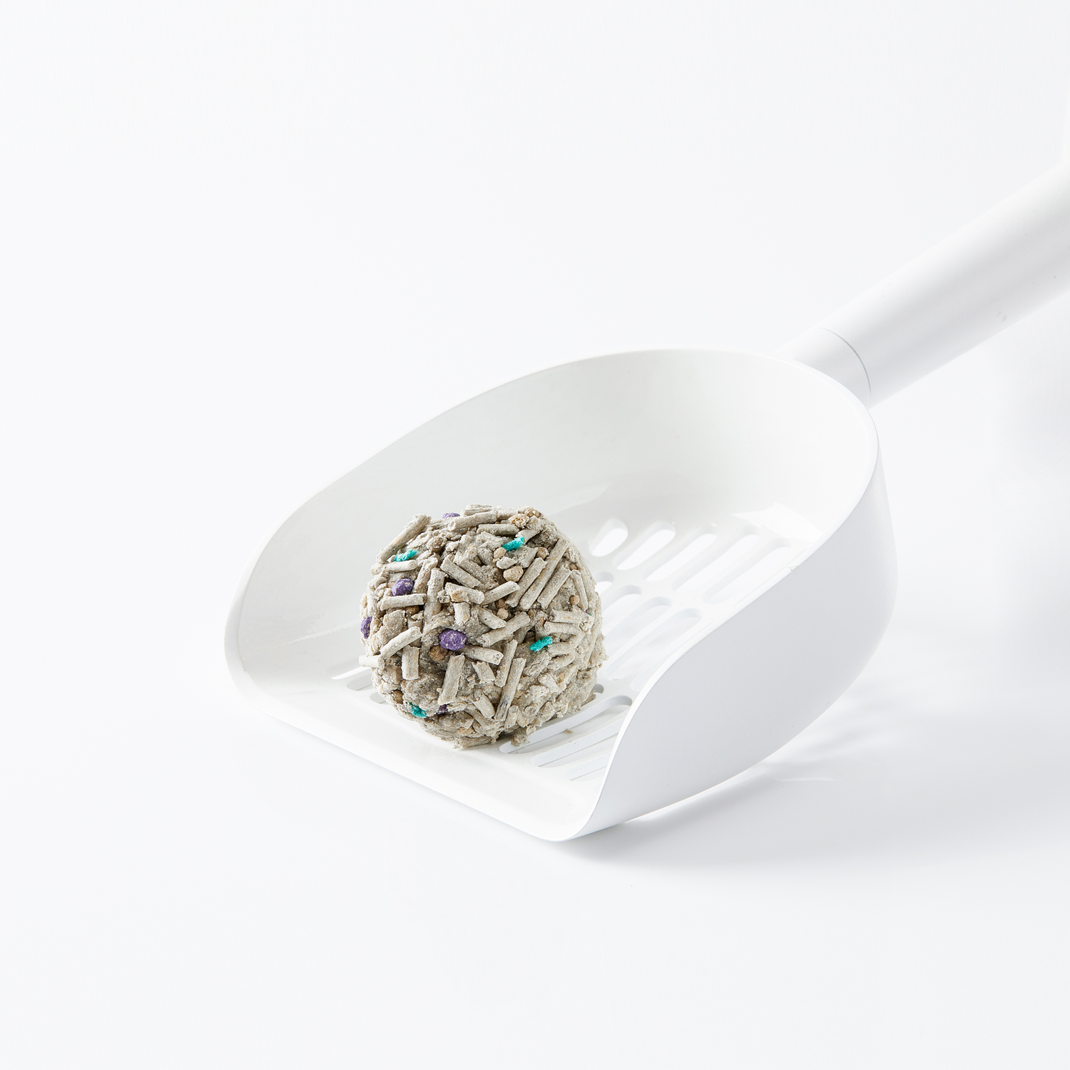 A scoop holding a clump of cat litter. The litter is gray with blue and green specs.