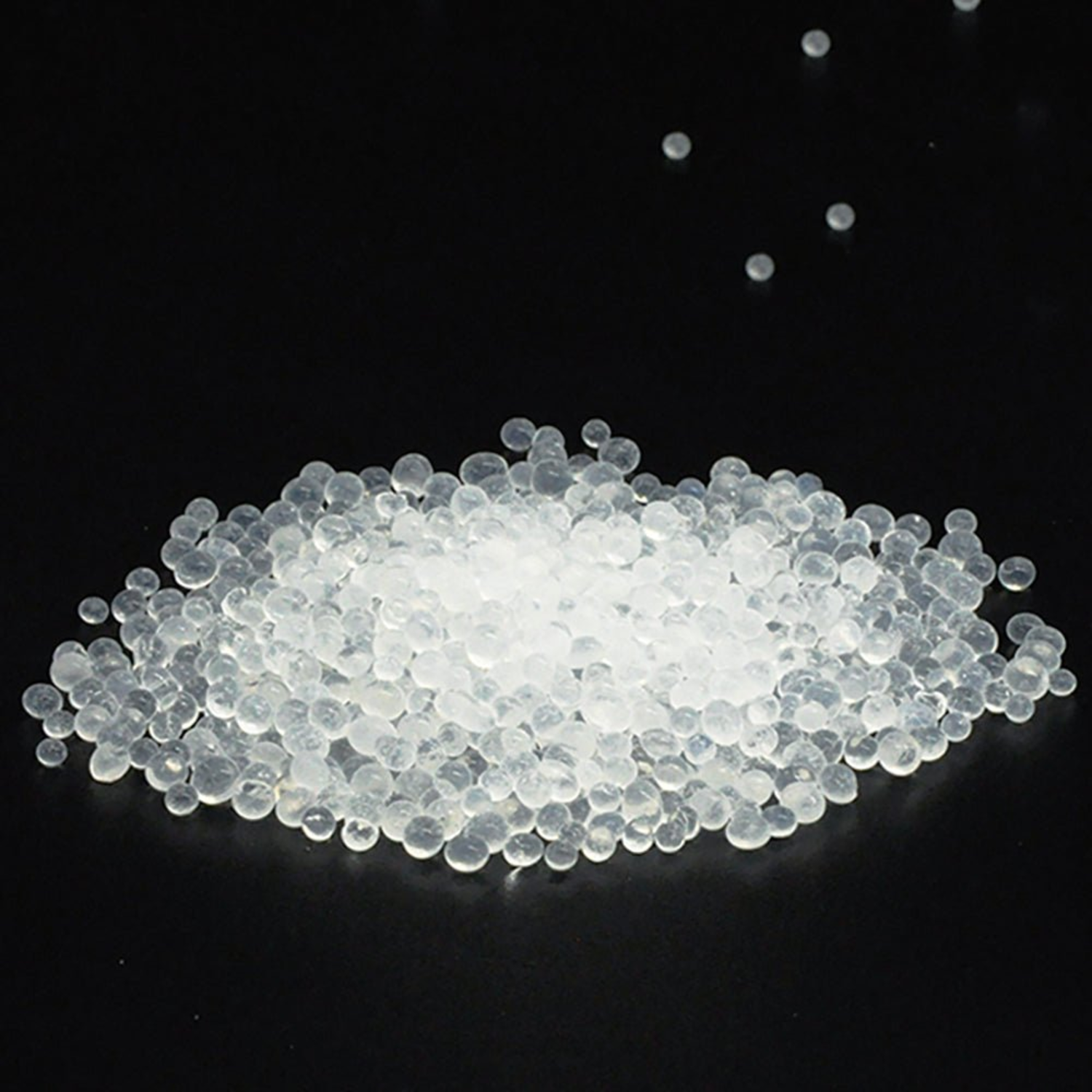 A pile of small, clear, spherical beads on a black background.