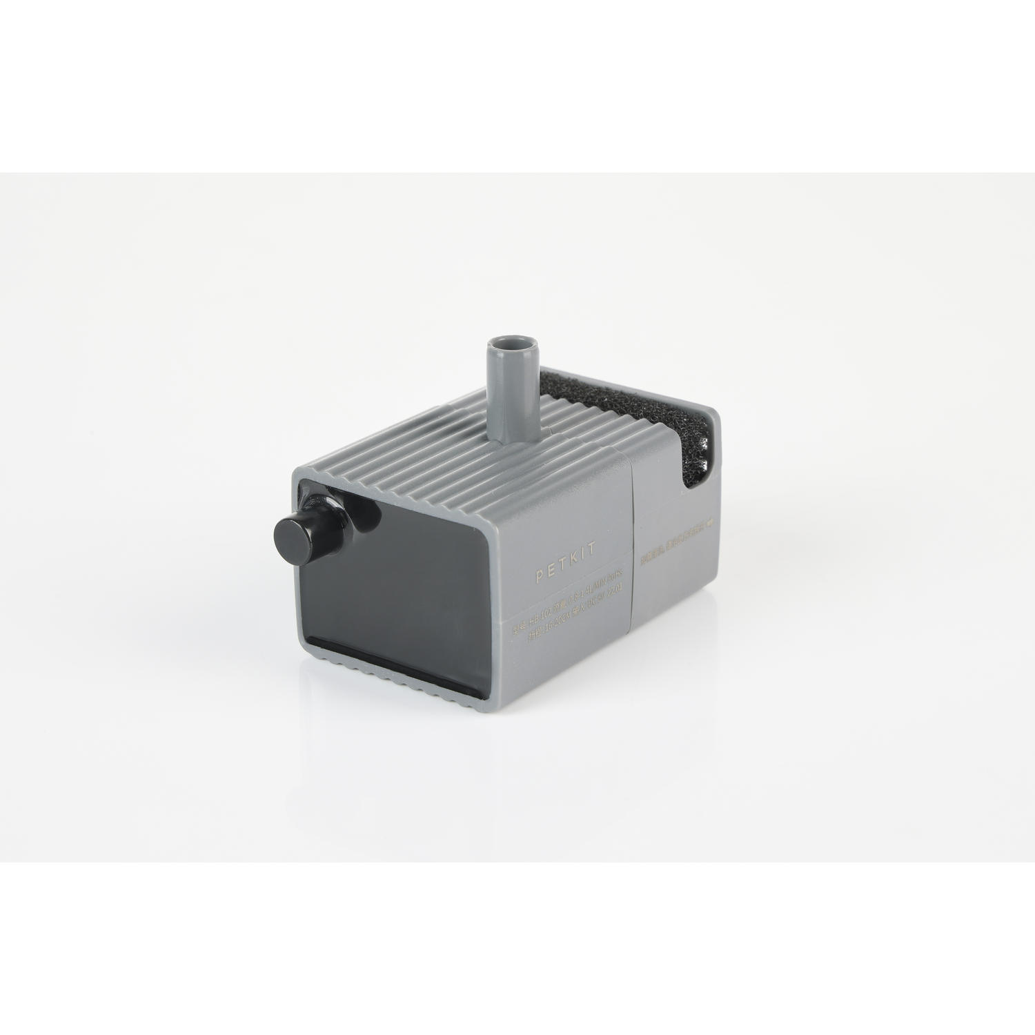 A gray box with a black knob and a tube. It is on a white surface.