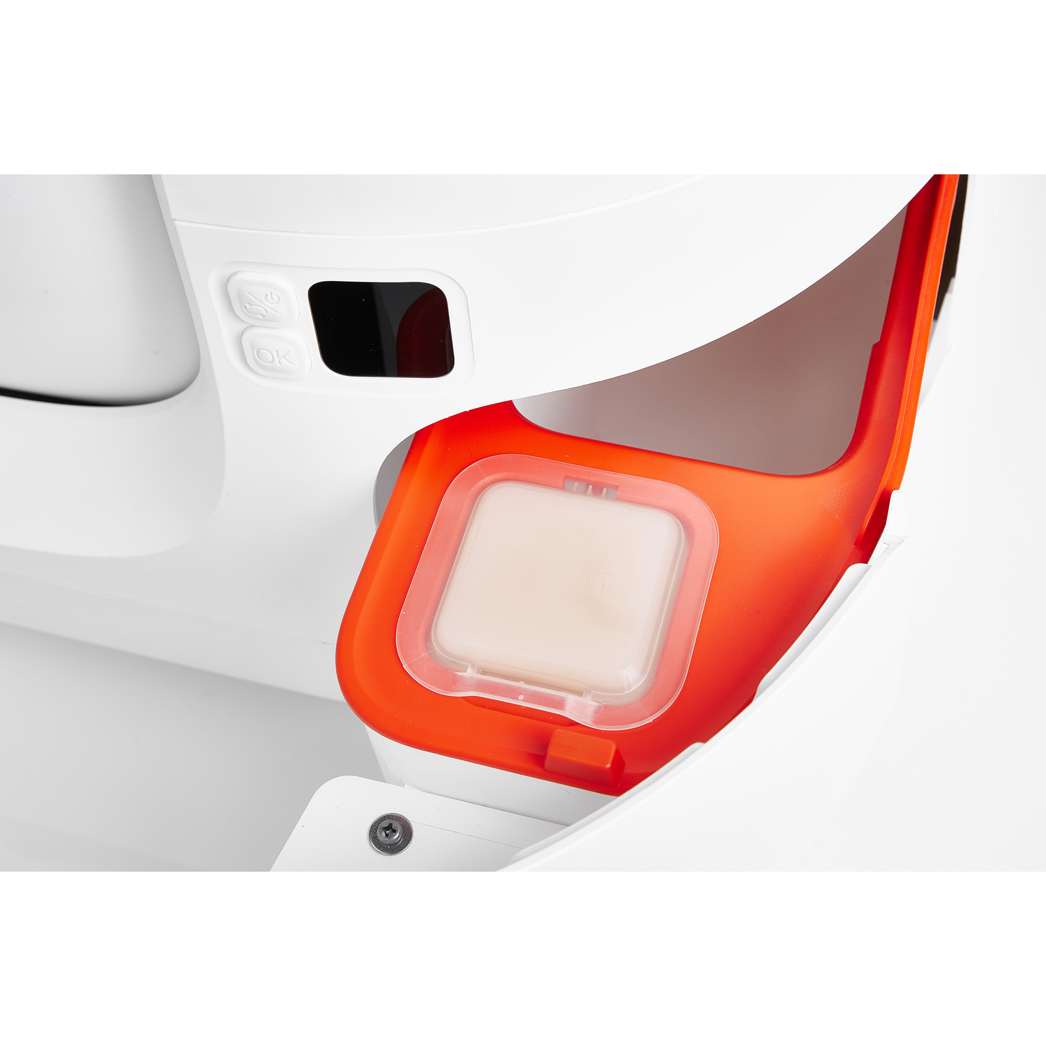 White machine part with a clear, orange container holding a white tablet.