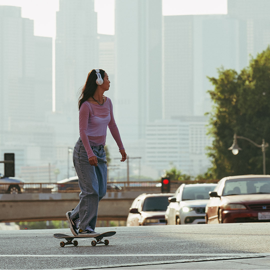 Frau fährt in der Stadt Skateboard, Gebäude im Hintergrund.