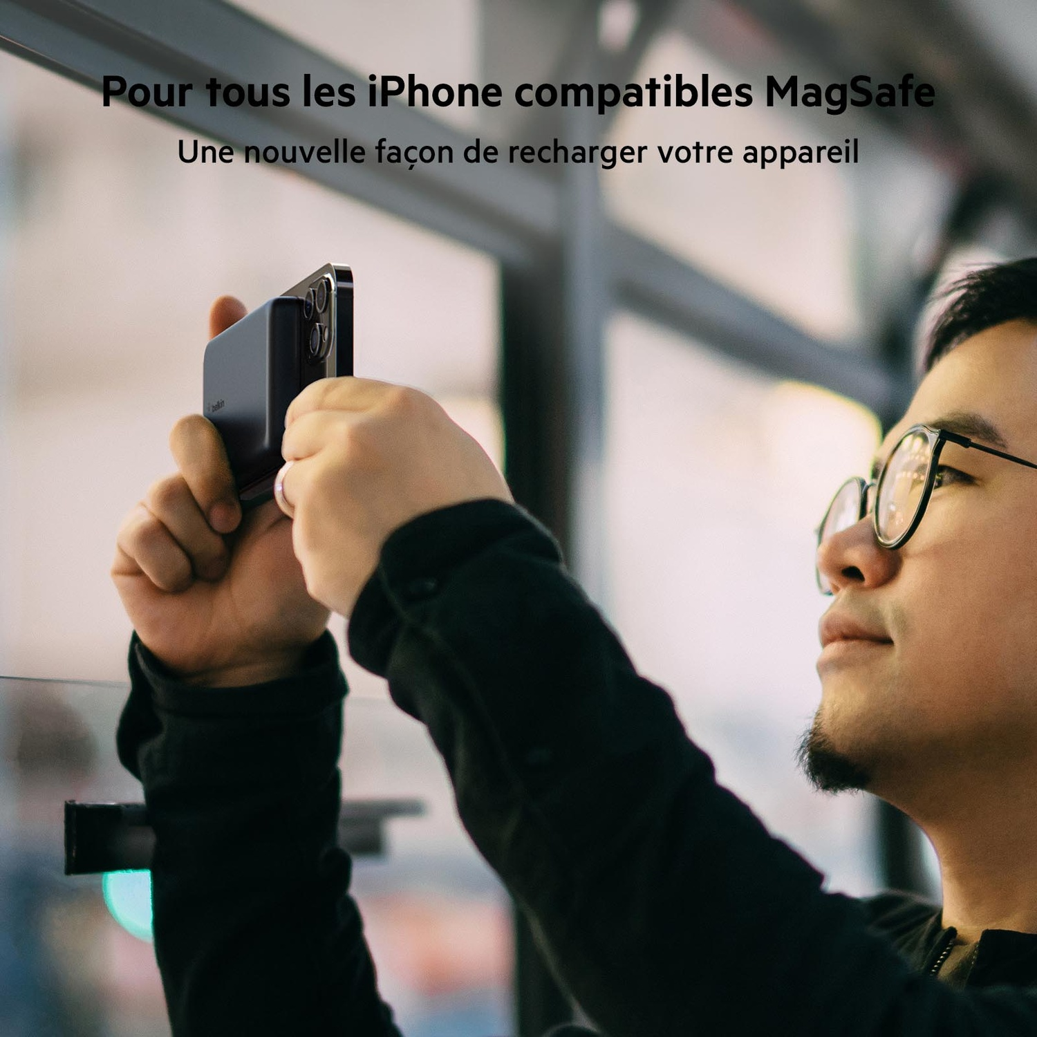 Homme tenant un téléphone près du visage, rechargeant un appareil, texte en français.